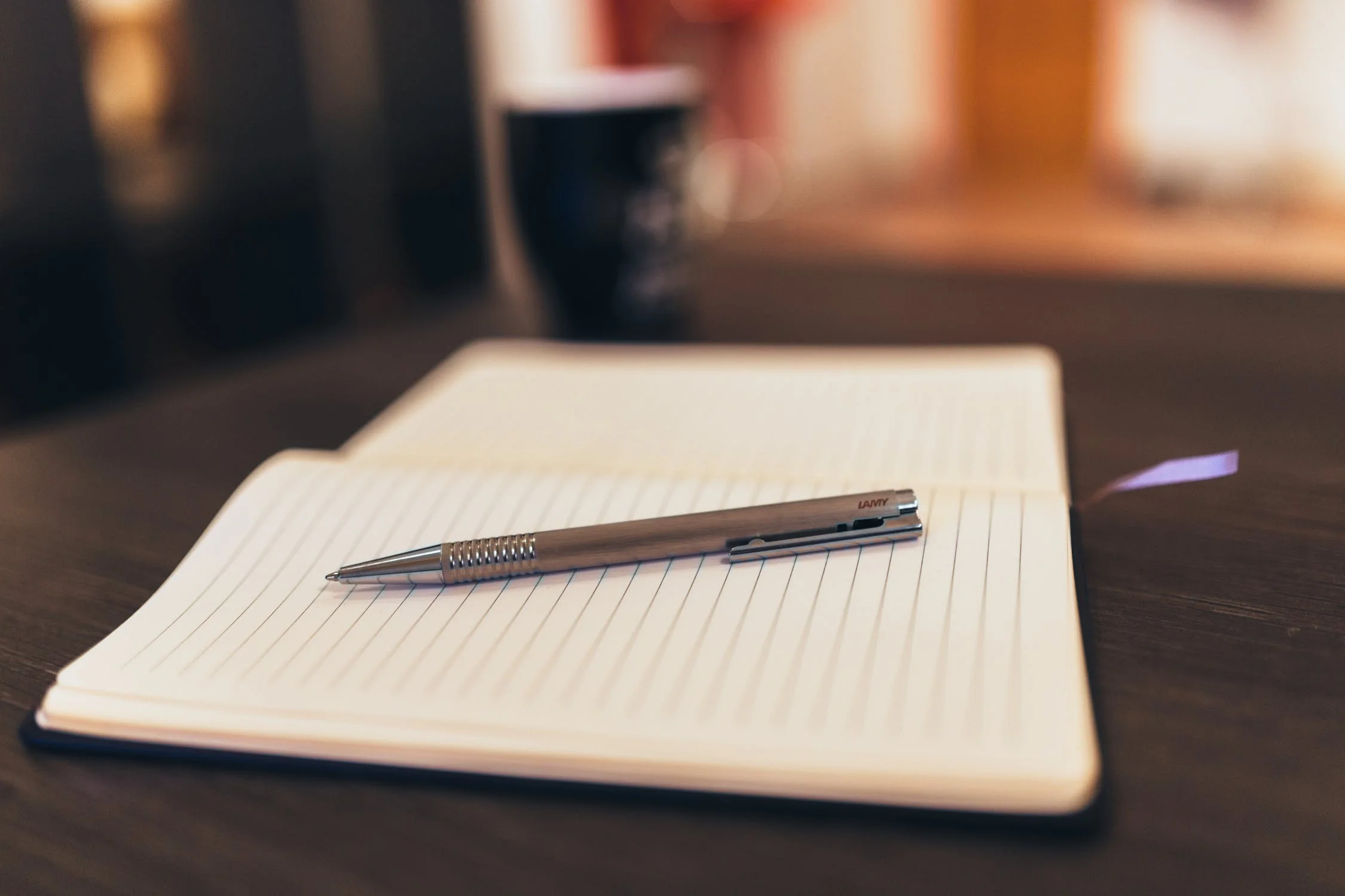 Pen resting on open, blank notebook.