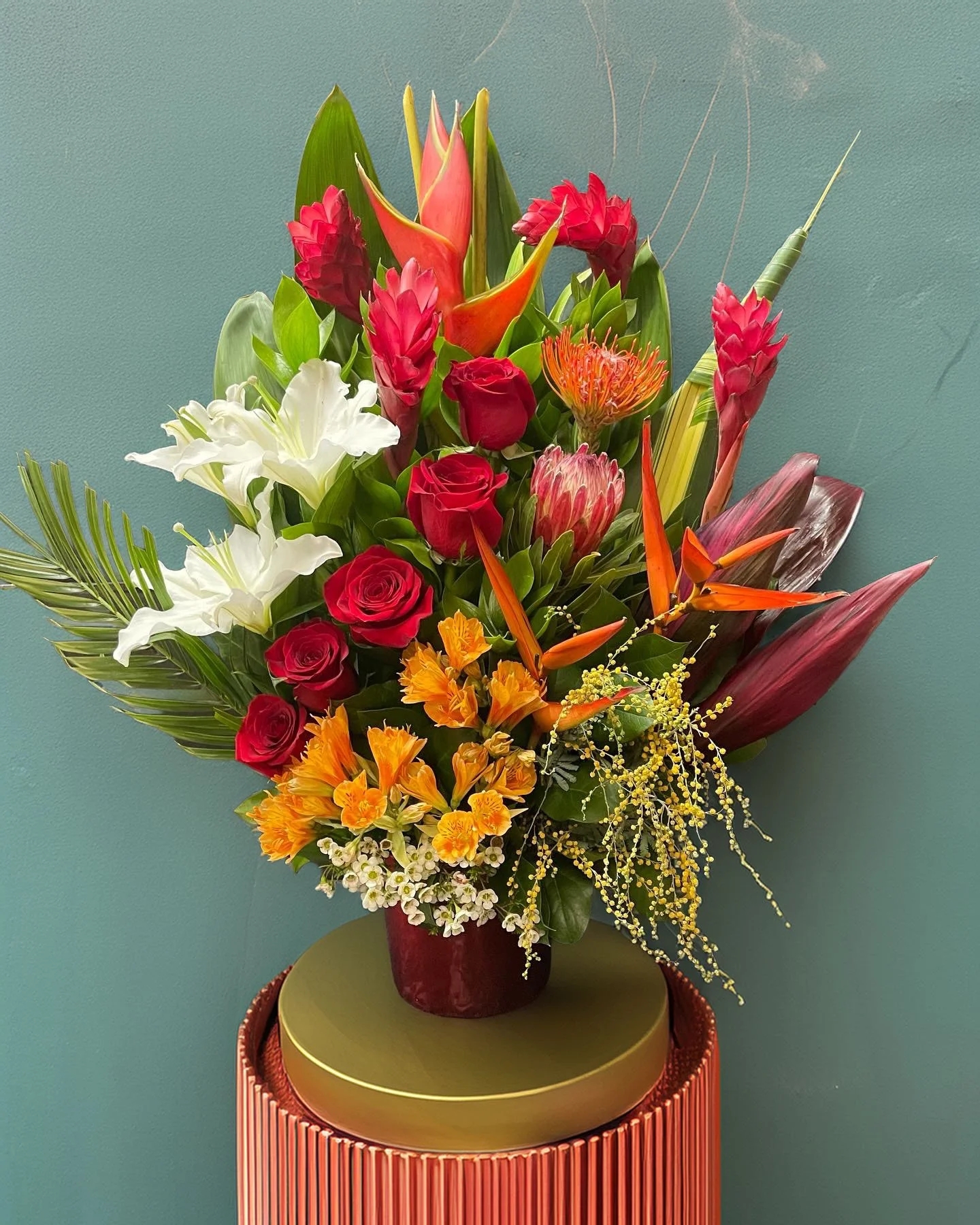 A vibrant bouquet of various colorful flowers arranged in a dark red vase.