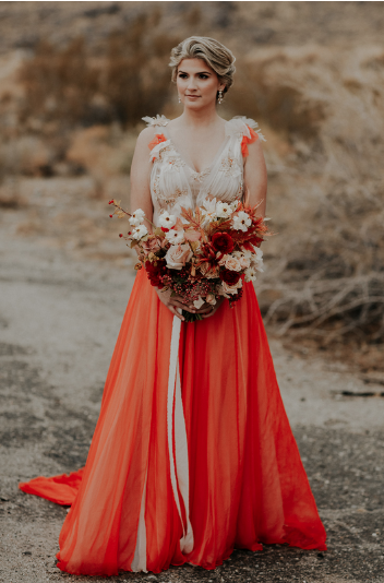  a bride wears a weddingdress with  a removable skirt in red/orange silk chiffon. red chiffon frills are embroidered onto the the gold textured bodice 