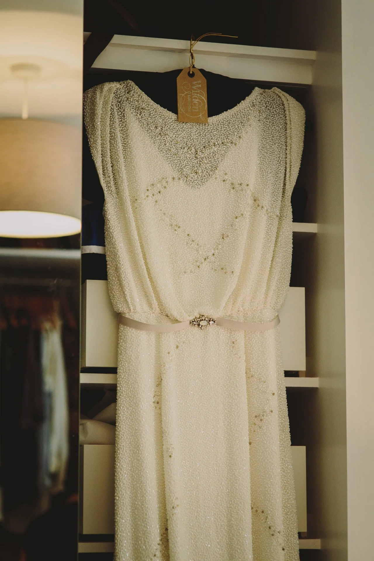  a white beaded 1930’s style wedding dress is further embroidered with slashes of silver and blue beads on the bodice. 