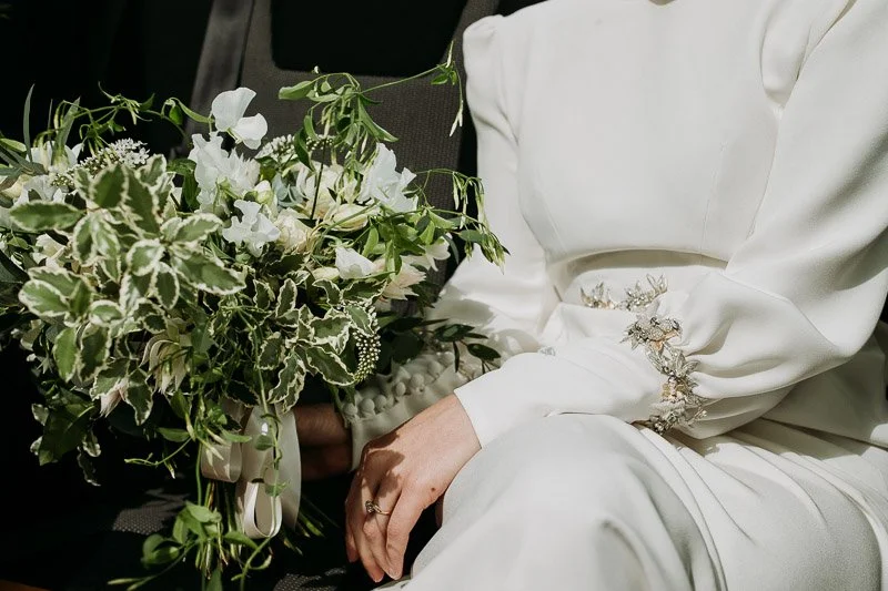 detail of a beaded cuff on a vintage style wedding dress. Silver thread motifs embroidered with beaded peyote flowers and vintage beads and crystals