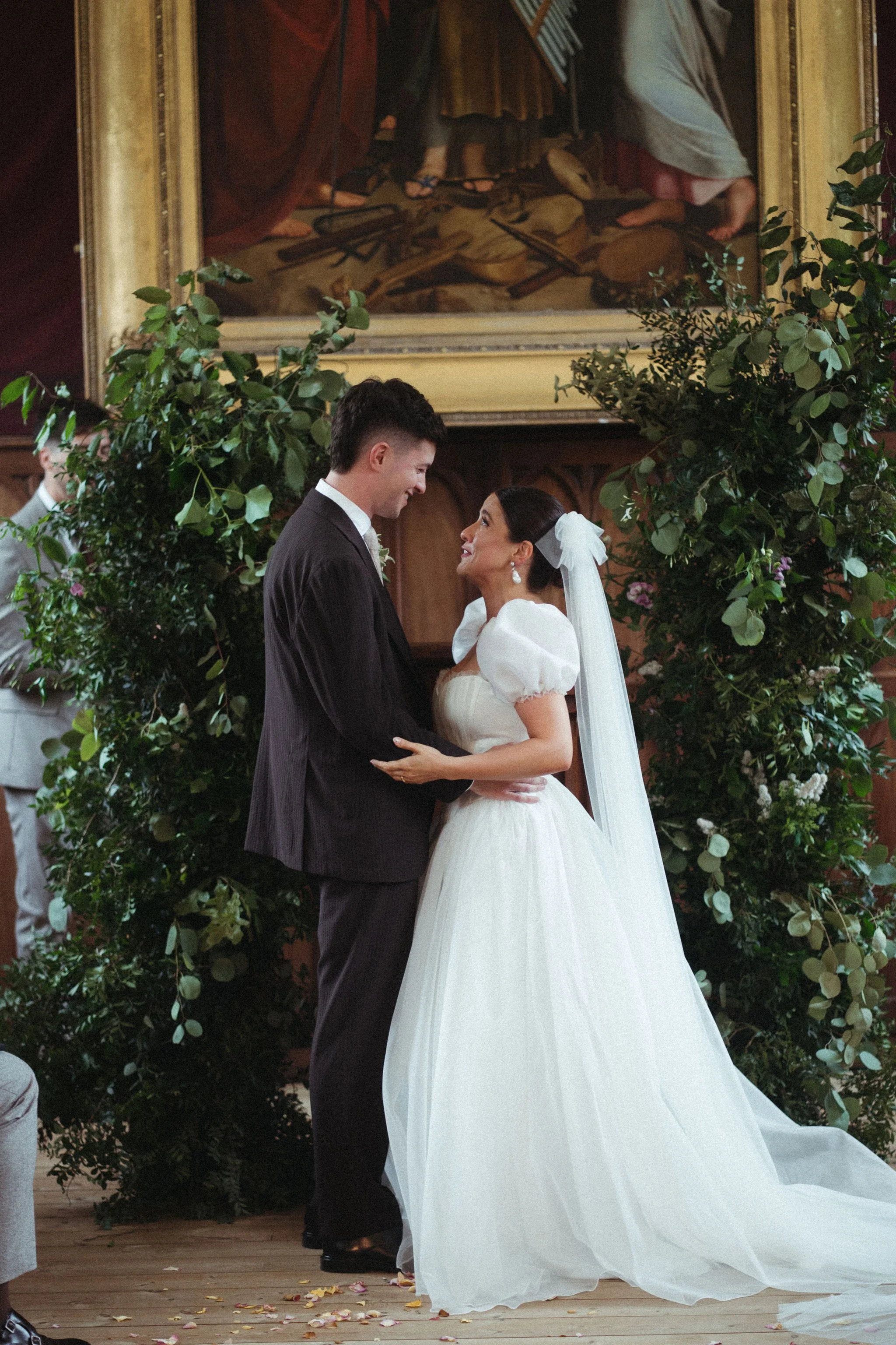 a bride and groom embrace, the bride wears a bespoke wedding dress of silk organza with cute short puff sleeves.