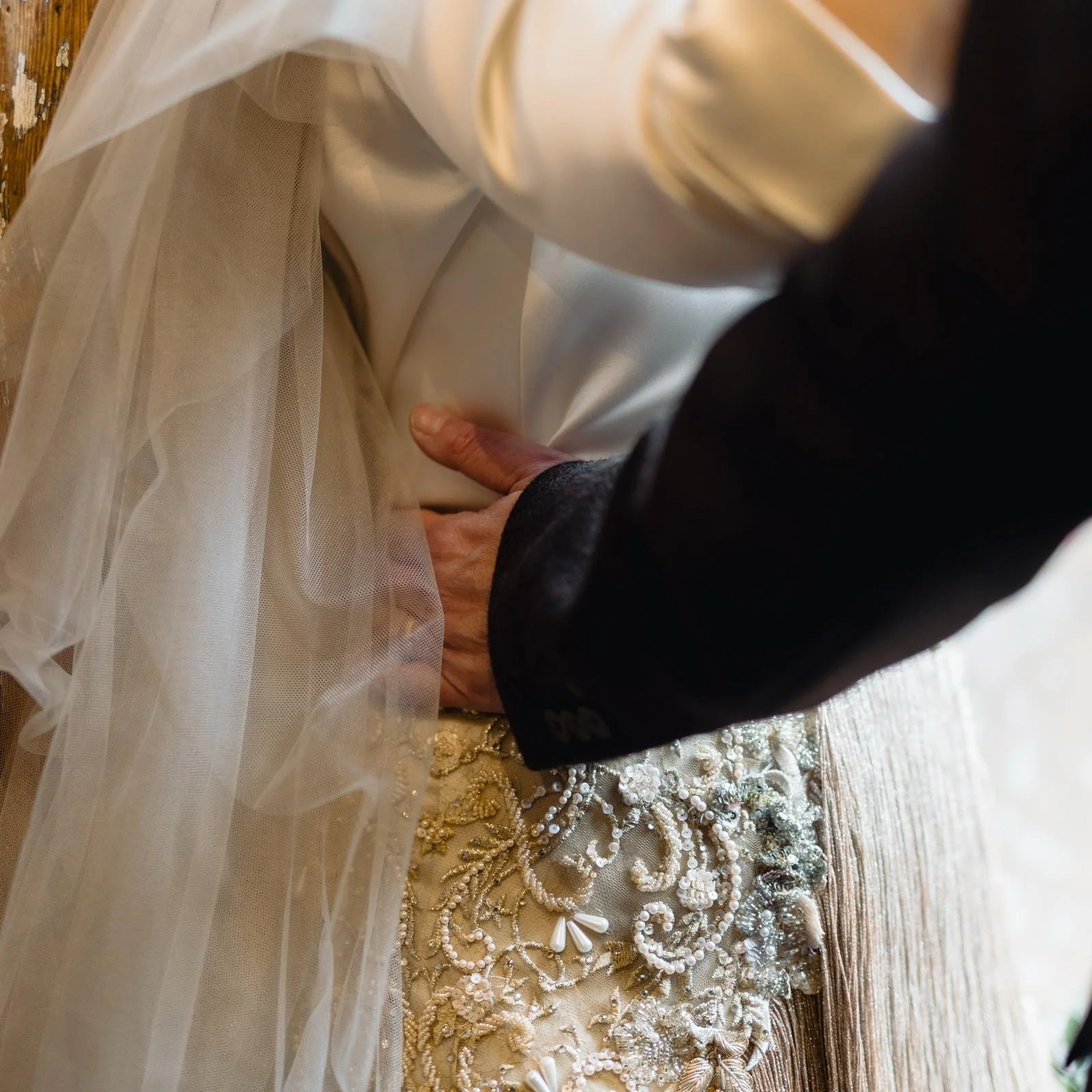 details of a bespoke wedding dress, showing the ivory silk of a blouse, and the hip detail showing gold silk embroidered with swirls of glass peads, pearls and lace, by Wilden London