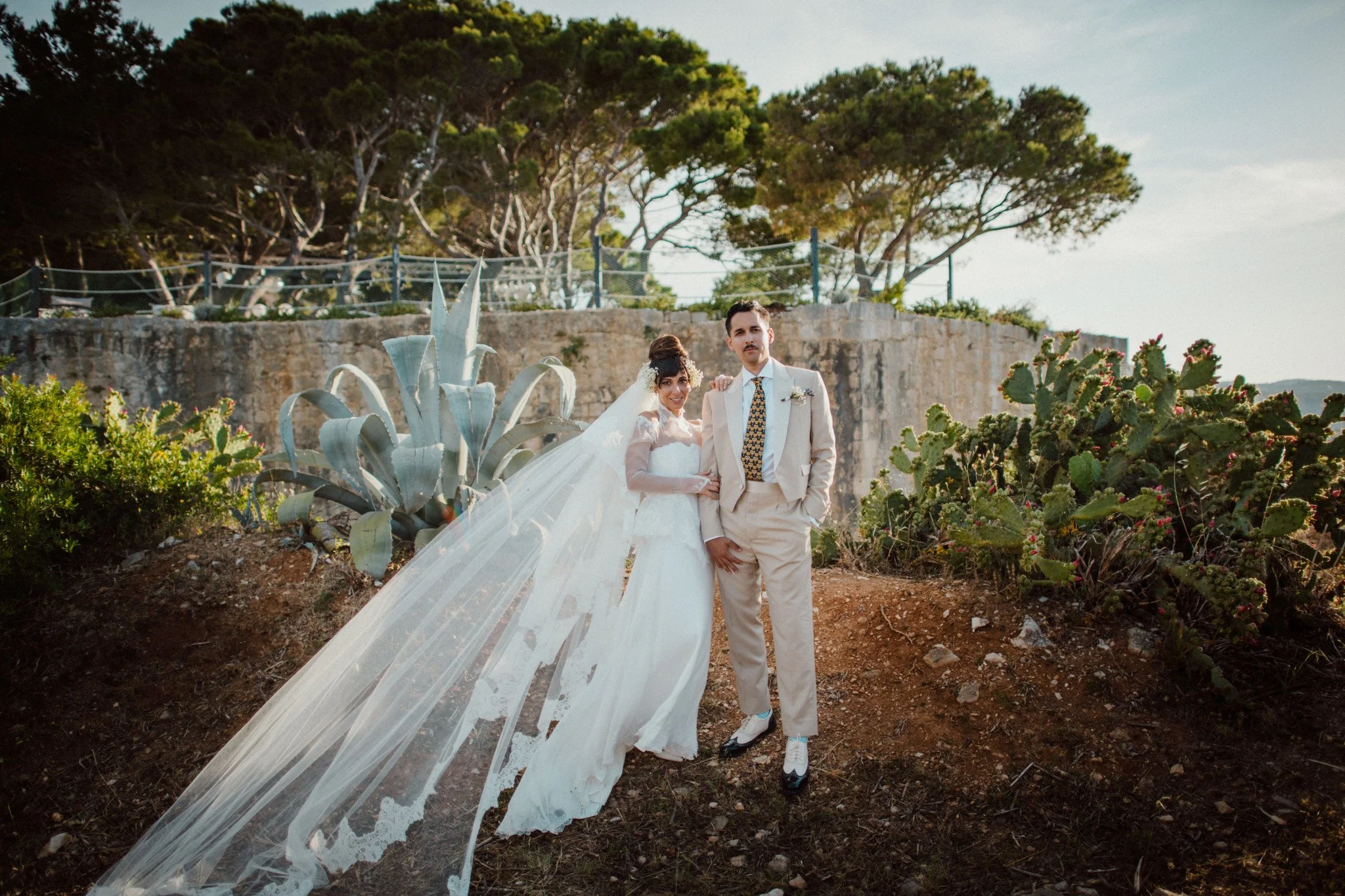 Art Director Lucrecia Taromina Tierney wears a bespoke silk wedding dress for her wedding on Vis Island in Croatia. The dress in hand embroidered with Rococo style lace, it's romantic, but with edgy and modern details.