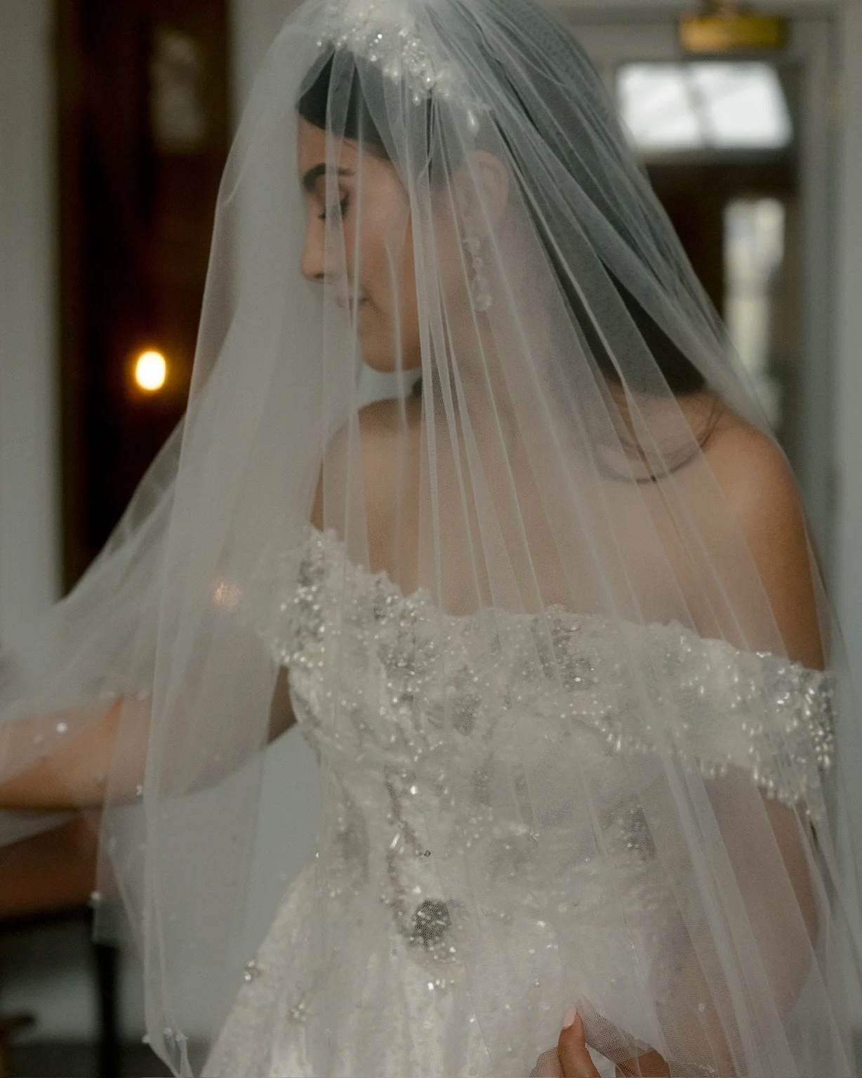 bride wears a persian heritage inspired ballgown wedding dress for her wedding at the signet library in edinburgh. The dress has persian motifs including water ripples, lotus, paisley and stars, in silver and pearl. worn with a decadent veil