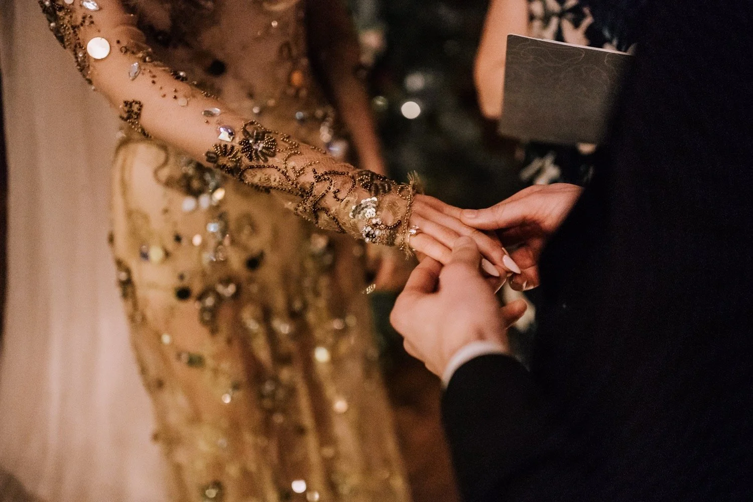 detail of a gold embellished wedding dress and the bride and groom exchange rings