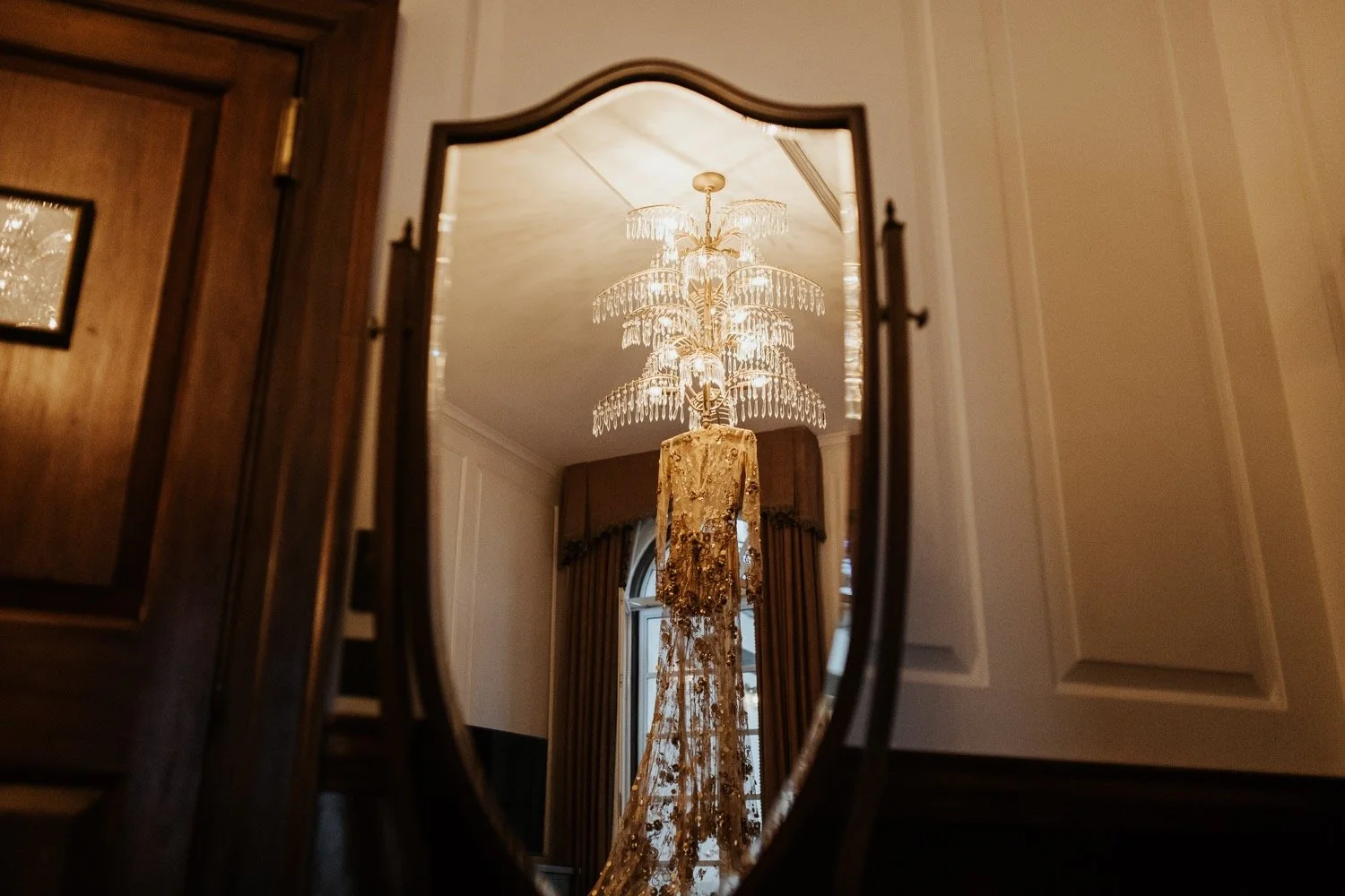 A gold wedding dress hangs from a glass chandelier at the ned in london