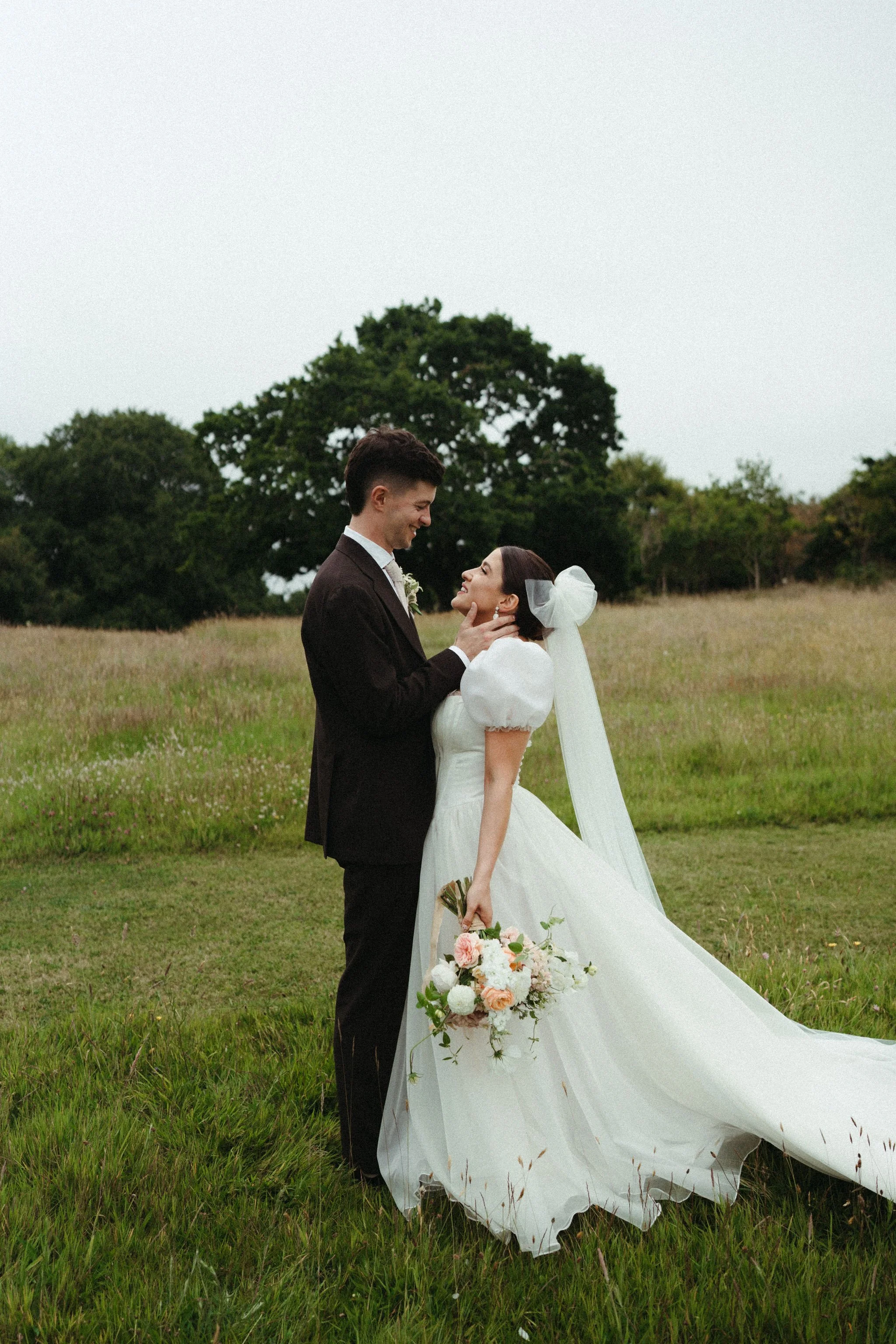 a gorgeous bride and groom taking portraits. the bride wears an organza ballgown wedding dress with pudd sleeves by wilden london