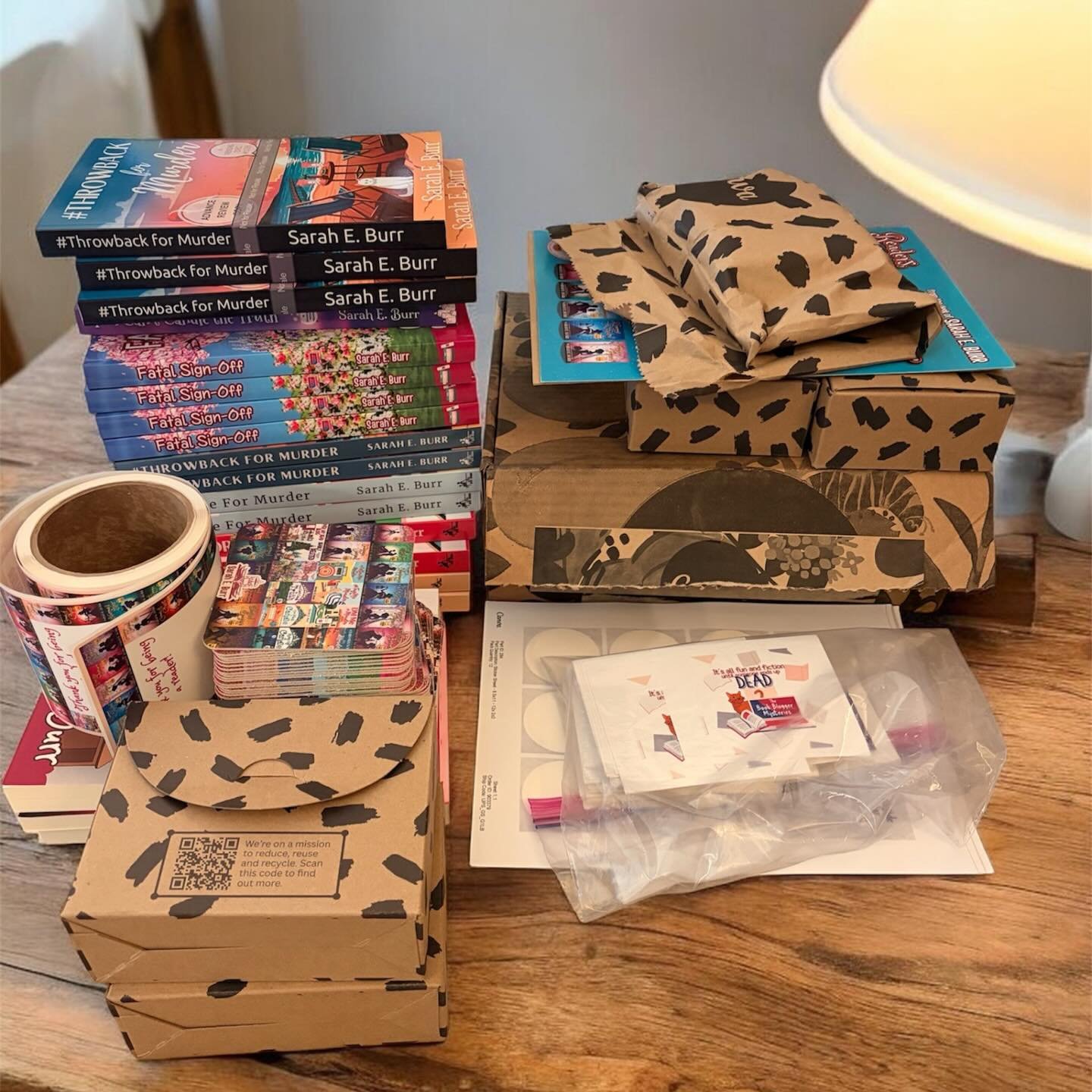 Prepping all my Malice swag, clearly brought to you by @canva 😂. Readers, I&rsquo;ve got bookmarks, coasters, stickers, bookplates, AND something extra special in that big box. Can&rsquo;t wait to share it with you! Come find me at Malice Domestic t