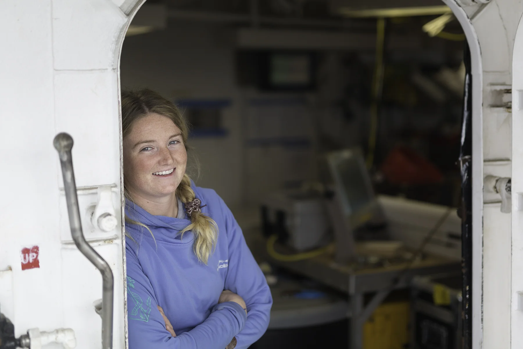 Portrait of Anna leaning against the hatch to the wet lab aboard the R/V Ocean Starr . Photo by Brendan Smith/NPRB
