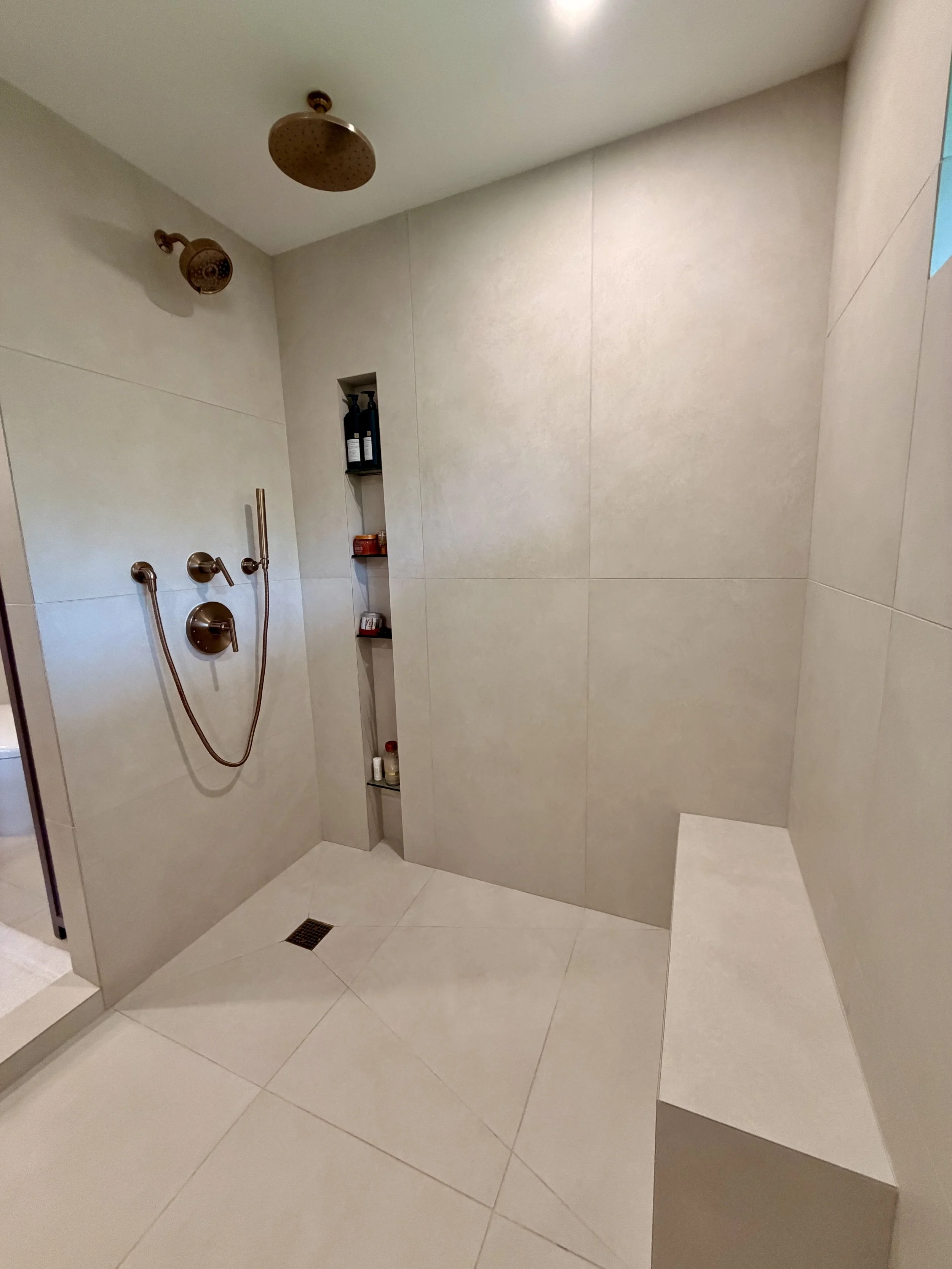 Bathroom remodel in Honolulu. New shower waterproof system, installation of  large format porcelain tile on floor and walls and custom designed soap niche and bench with mitered corners