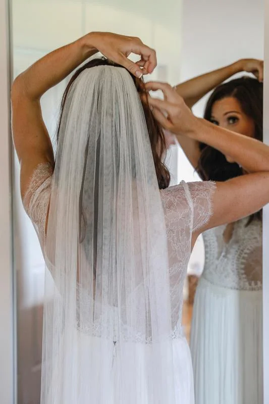 Bride putting in veil before wedding
