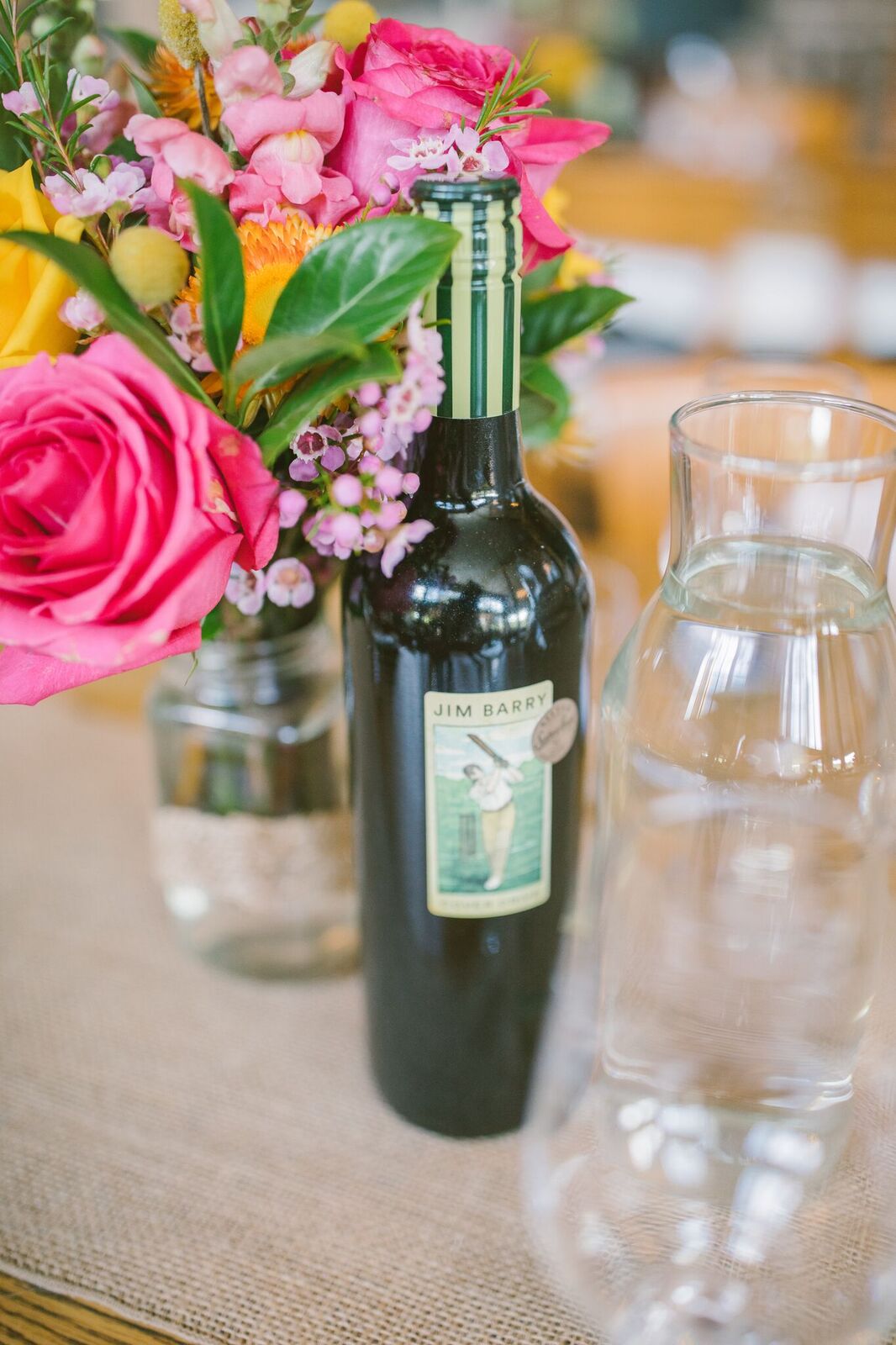 Bottle of wine with pink, purple and yellow wedding flowers