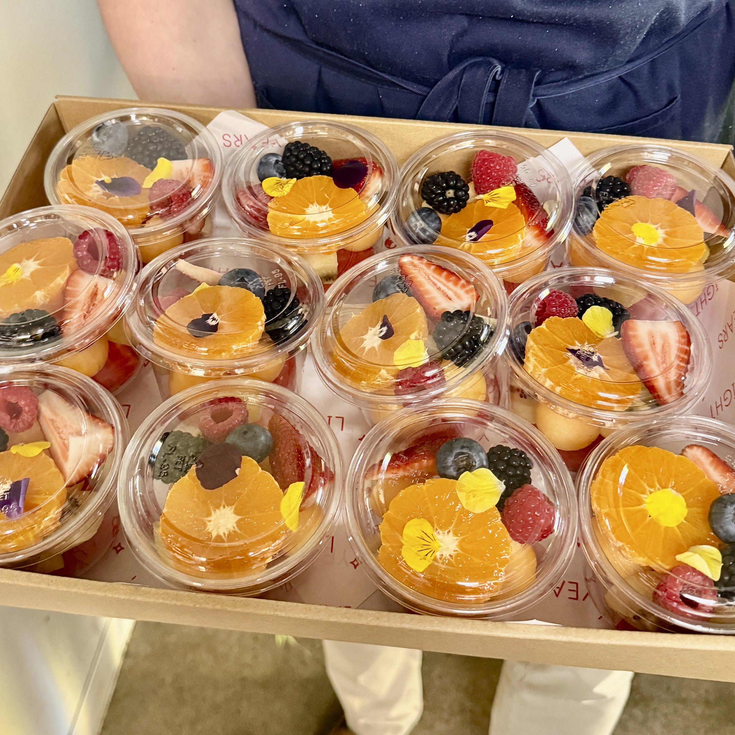 Individual fresh fruit cups arranged in trays for corporate catering and office morning tea in Melbourne.