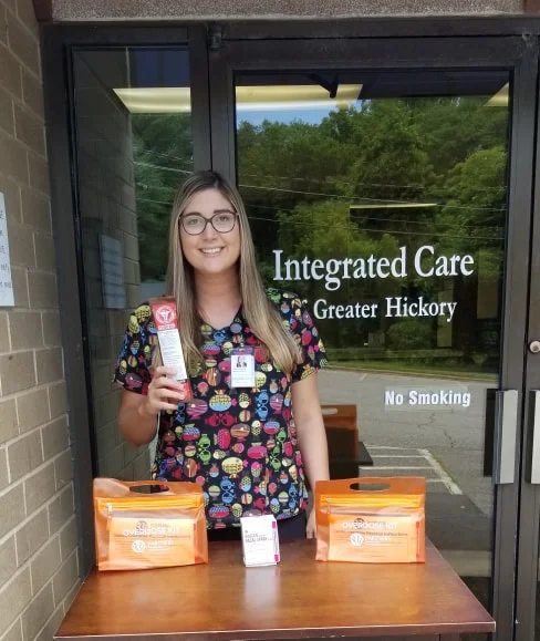 What is naloxone? Naloxone is a medication designed to rapidly reverse opioid overdose. It is an opioid antagonist—meaning that it binds to opioid receptors and can reverse and block the effects of other opioids. It can very quickly restore normal respiration to a person whose breathing has slowed or stopped as a result of overdosing with heroin or prescription opioid pain medications. How is naloxone given? There are three FDA-approved formulations of naloxone: Injectable (professional training required) Generic brands of injectable naloxone vials are offered by a variety of companies that are listed in the FDA Orange Book under "naloxone" (look for "injectable"). Note: There has been widespread use of improvised emergency kits that combine an injectable formulation of naloxone with an atomizer that can deliver naloxone intranasally. Use of this product requires the user to be trained on proper assembly and administration. These improvised intranasal devices may not deliver naloxone levels equivalent to FDA-approved products. In fact, the manufacturer of an internasal atomizer device issued a voluntary recall on 10/27/16 noting that some of the devices “may not deliver a fully atomized plume of medication, making the drug potentially less effective.” An approved, prefilled nasal spray is now available (see below). Autoinjectable EVZIO® is a prefilled auto-injection device that makes it easy for families or emergency personnel to inject naloxone quickly into the outer thigh. Once activated, the device provides verbal instruction to the user describing how to deliver the medication, similar to automated defibrillators. Prepackaged Nasal Spray NARCAN® Nasal Spray is a prefilled, needle-free device that requires no assembly and is sprayed into one nostril while patients lay on their back. Note: Both NARCAN® Nasal Spray and EVZIO® are packaged in a carton containing two doses to allow for repeat dosing if needed. They are relatively easy to use and suitable for home use in emergency situations. Who can give naloxone to someone who has overdosed? The liquid for injection is commonly used by paramedics, emergency room doctors, and other specially trained first responders. To facilitate ease of use, NARCAN® Nasal Spray is now available, which allows for naloxone to be sprayed into the nose. While improvised atomizers have been used in the past to convert syringes for use as nasal spray, these may not deliver the appropriate dose. Depending on the state you live in, friends, family members, and others in the community may give the auto-injector and nasal spray formulation of naloxone to someone who has overdosed. Some states require a physician to prescribe naloxone; in other states, pharmacies may distribute naloxone in an outpatient setting without bringing in a prescription from a physician. To learn about the laws regarding naloxone in your state, see the Prescription Drug Abuse Policy System website. What dose can be provided? The dose varies depending on the formulation, and sometimes more than one dose is needed to help the person start breathing again. Anyone who may have to use naloxone should carefully read the package insert that comes with the product. You can find copies of the package insert for EVZIO® and NARCAN® Nasal Spray on the FDA website. What precautions are needed when giving naloxone? People who are given naloxone should be observed constantly until emergency care arrives and for at least 2 hours by medical personnel after the last dose of naloxone to make sure breathing does not slow or stop. What are the side effects of naloxone? Naloxone is an extremely safe medication that only has a noticeable effect in people with opioids in their systems. Naloxone can (but does not always) cause withdrawal symptoms which may be uncomfortable, but are not life-threatening; on the other hand, opioid overdose is extremely life-threatening. Withdrawal symptoms may include headache, changes in blood pressure, rapid heart rate, sweating, nausea, vomiting, and tremors. We provide free Narcan to our participants and train each person how to use this product to save lives. We ourselves carry this medication, so we are ready to save a life in the community. The NC Good Samaritan Law protects those who administer this medication to help save a life.