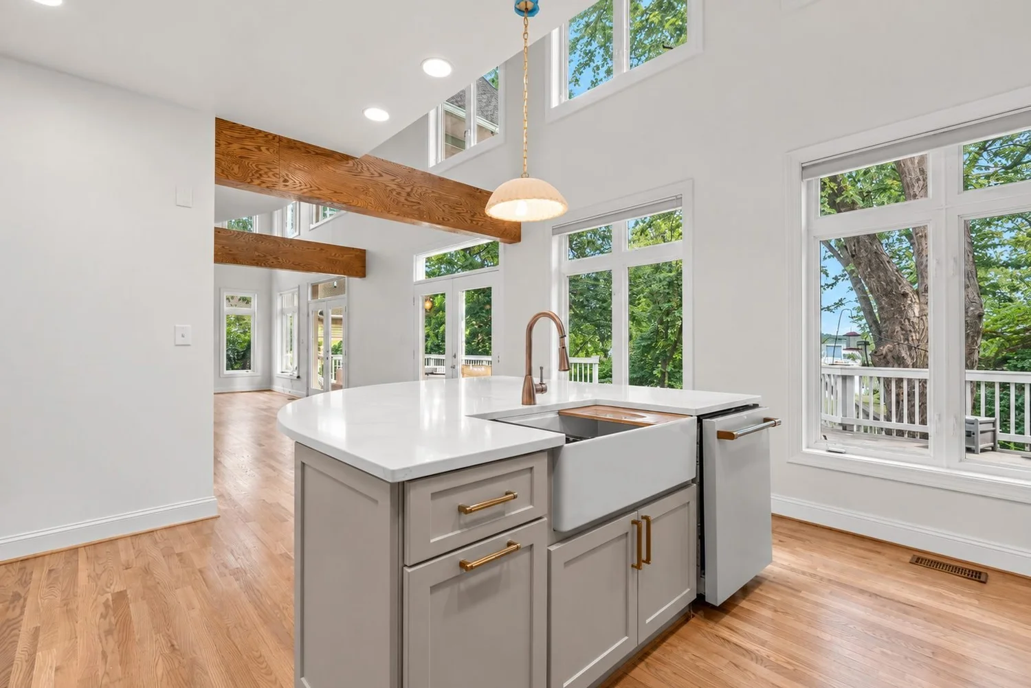 Kitchen Remodel with Island and Wood Beams Remodeled kitchen in Maryland with a white island, farmhouse sink, gray shaker cabinets and exposed wood beams