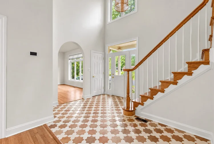 Foyer and Staircase Renovation Renovated two-story foyer with a star-pattern tile floor, wood staircase and white railings