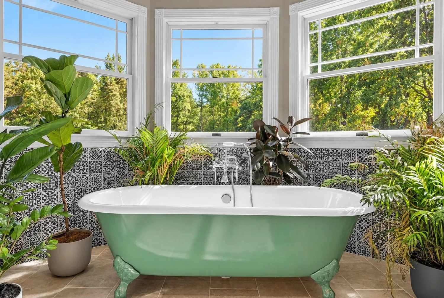 Bathroom Remodel with Clawfoot Tub Bathroom remodel with a green clawfoot tub, patterned tile wainscot and a wall of windows