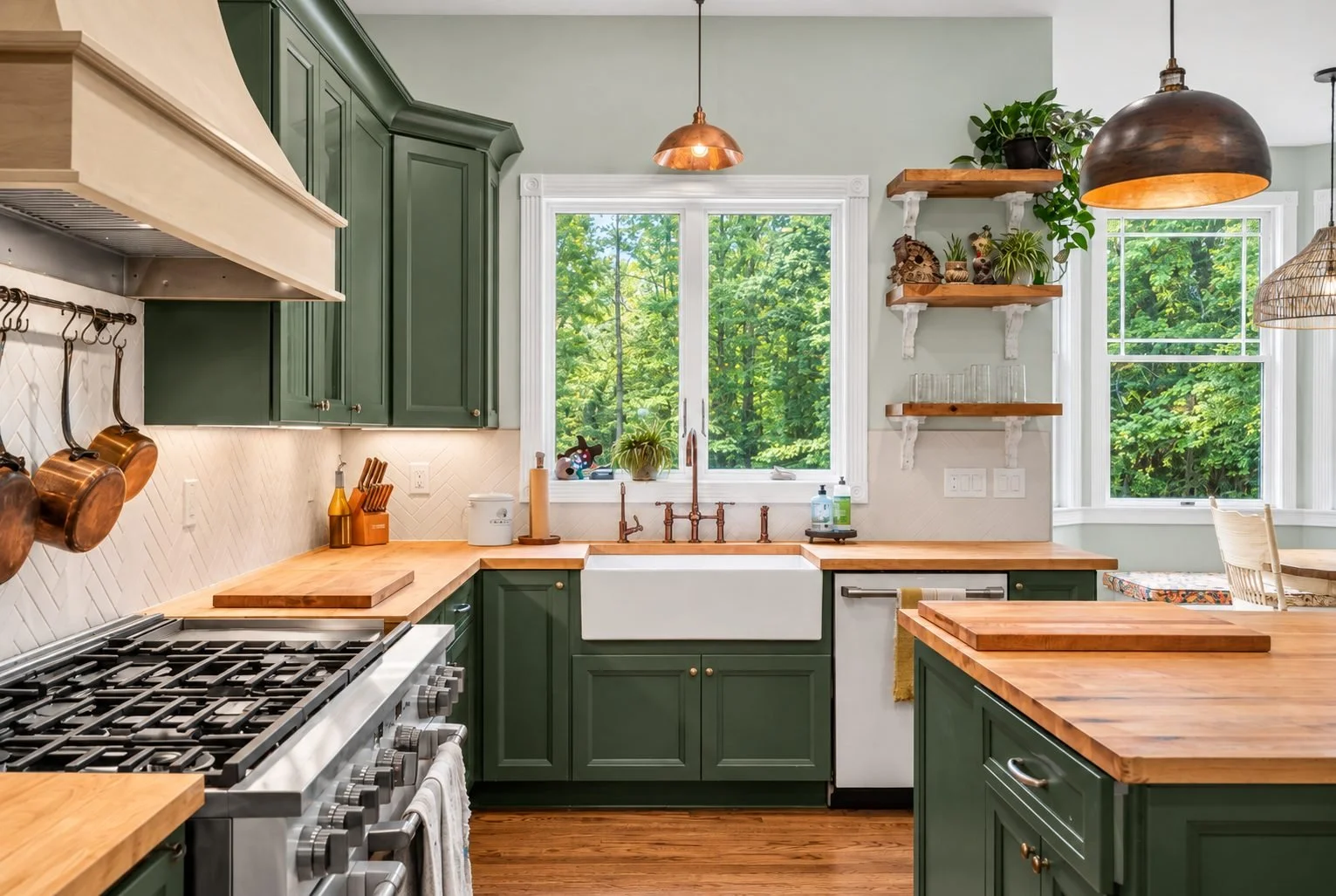 Green kitchen remodel with butcher block counters, farmhouse sink, copper fixtures and a wood range hood