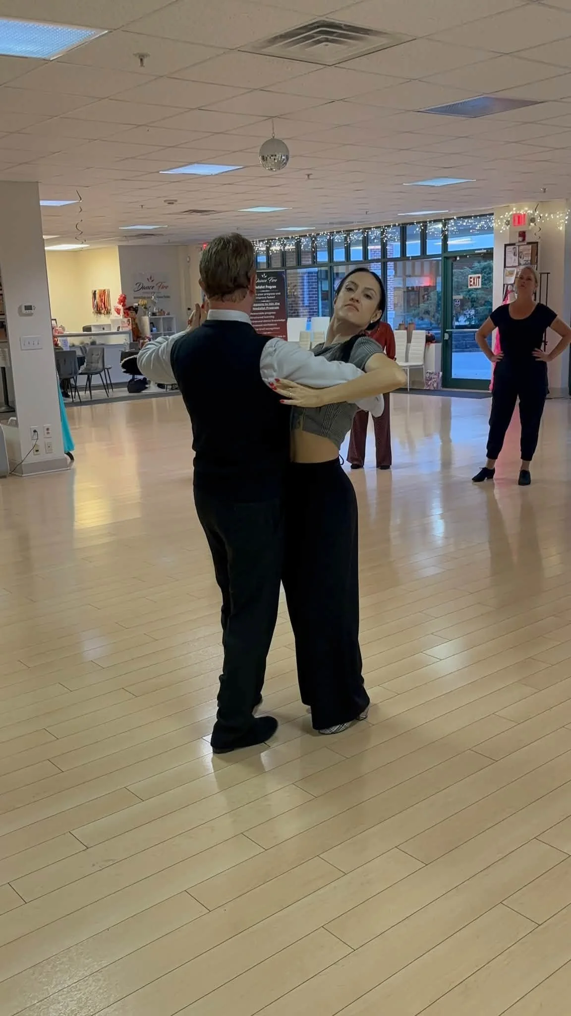 A ballroom couple practices in front of the Dance Fire studio mirrors