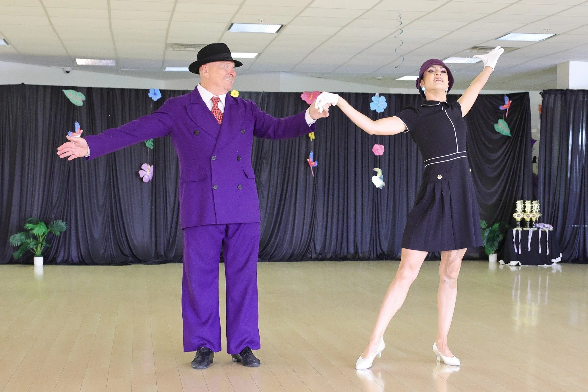 A dancer in a purple suit performs with his partner at the Summer Showcase