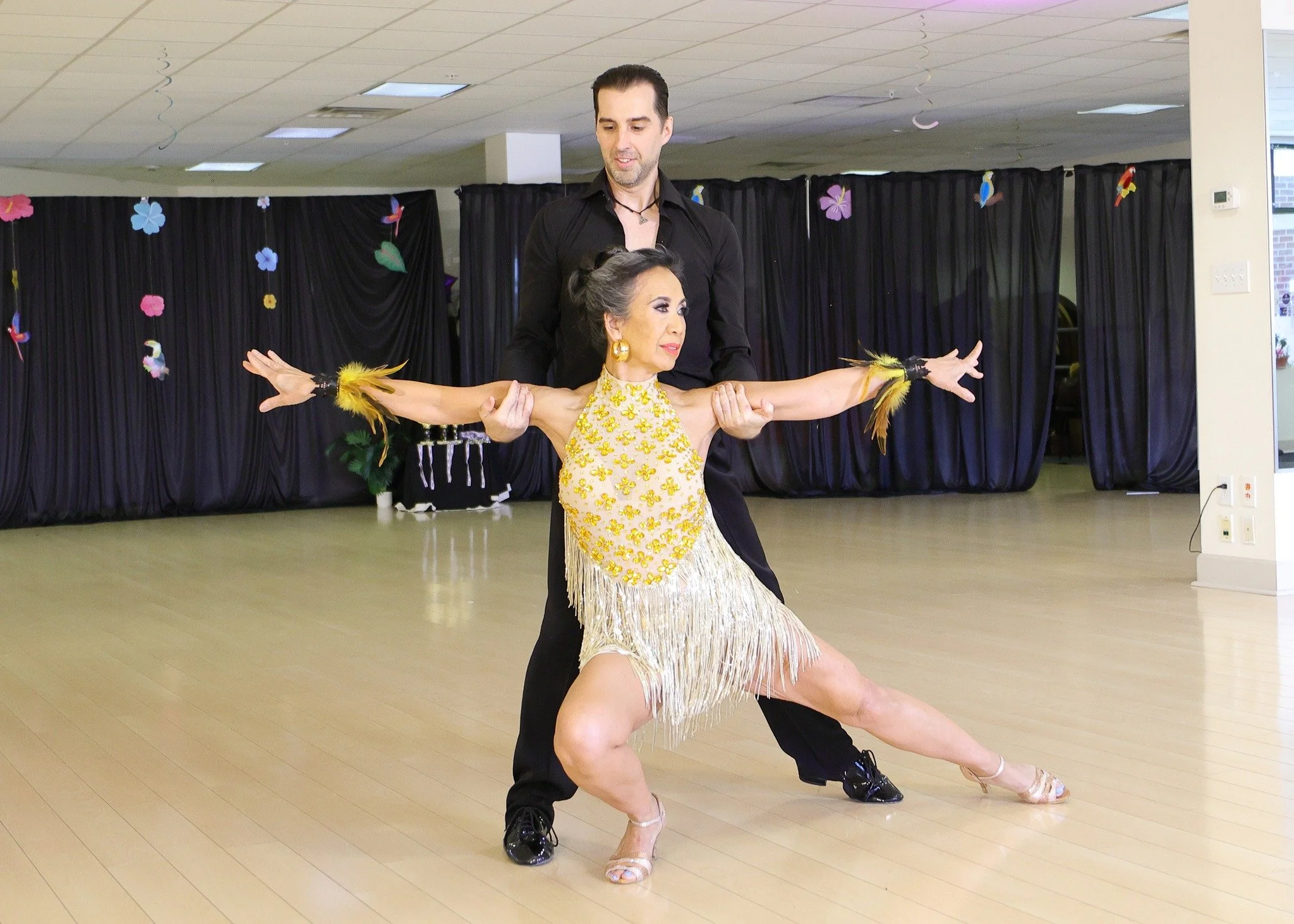 A dancer in a pink dress extends outward in hold with her partner
