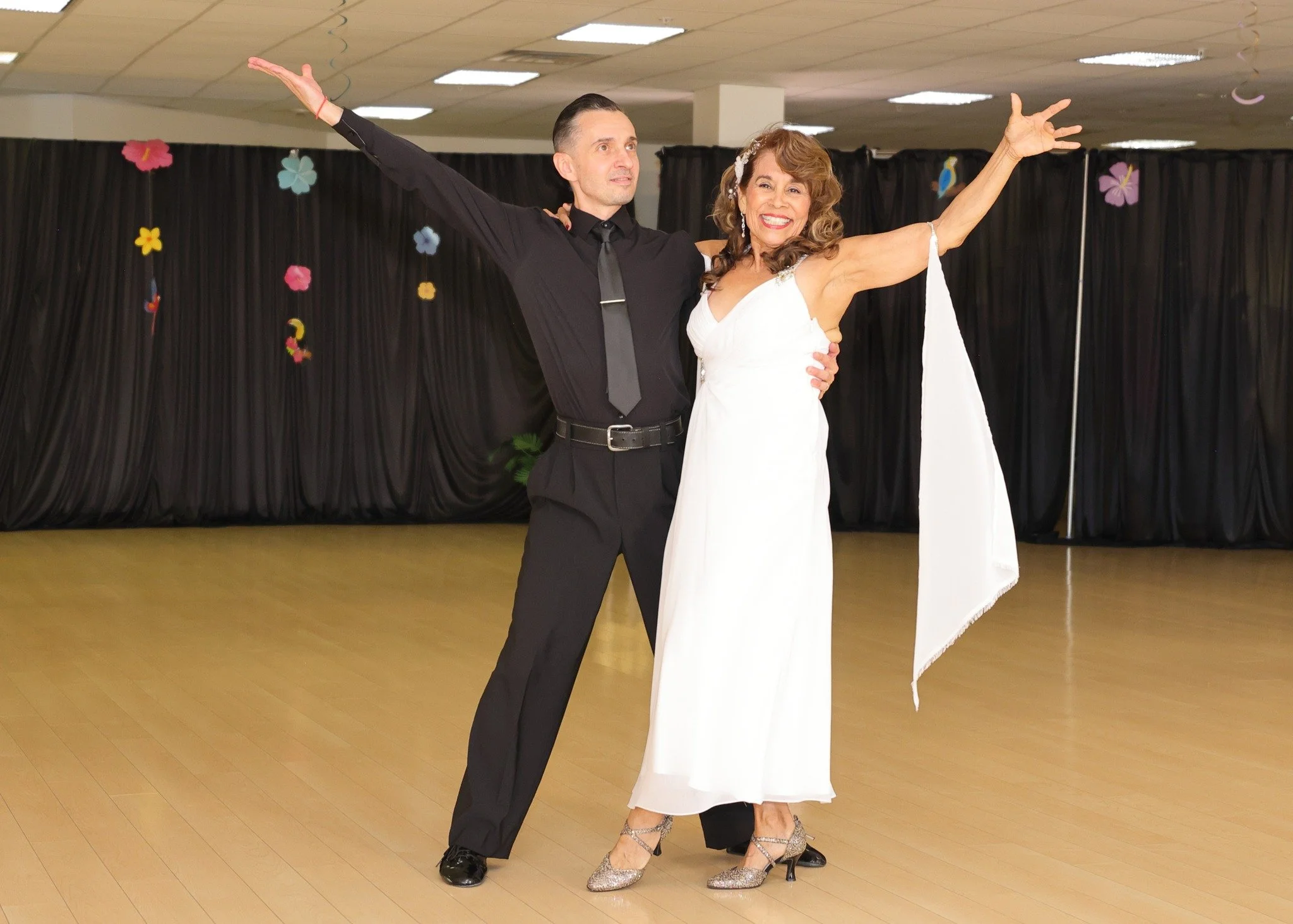 A dancer in white extends her arms beside her partner during a showcase routine