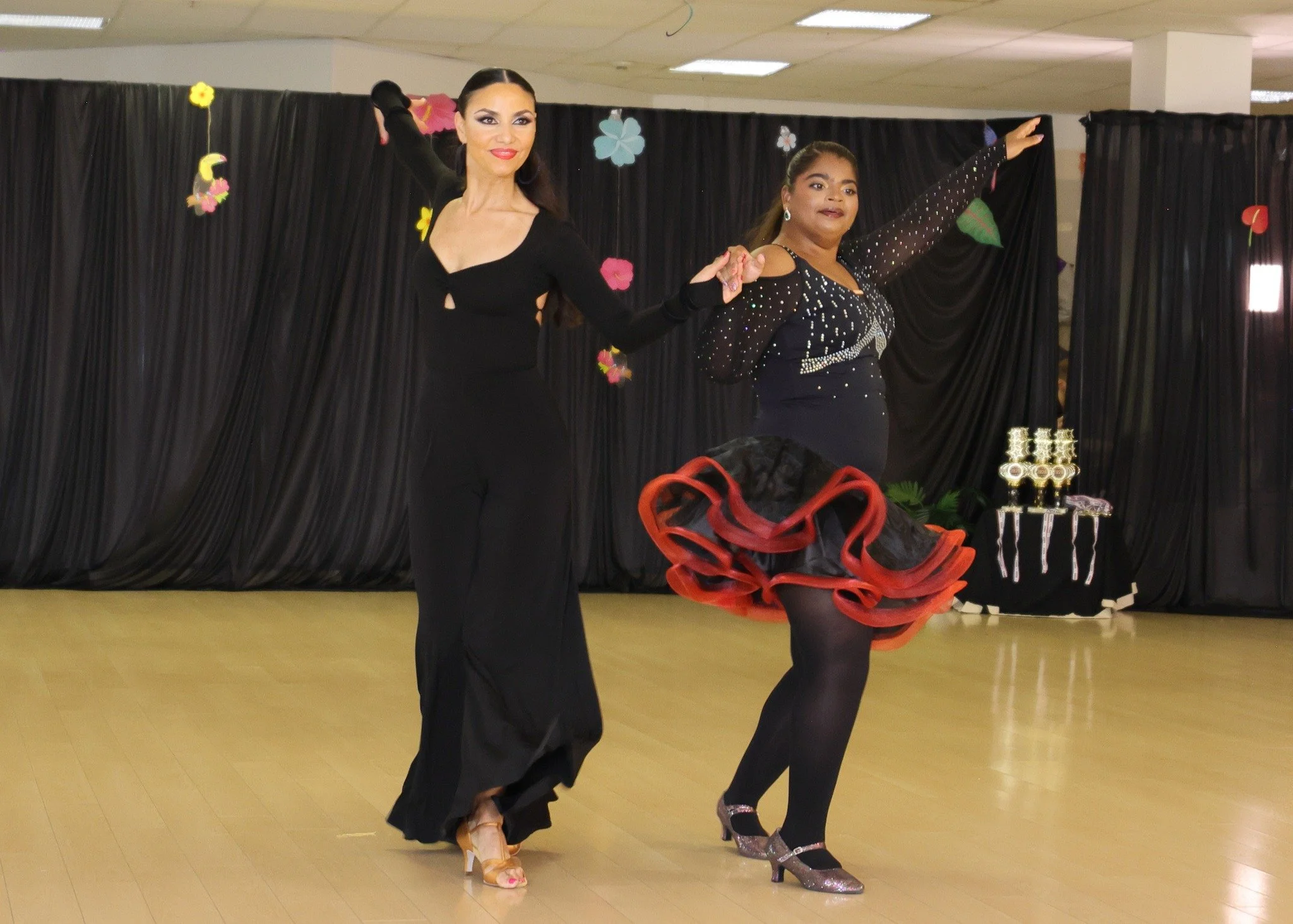Two dancers in black costumes perform a Latin-style showcase routine