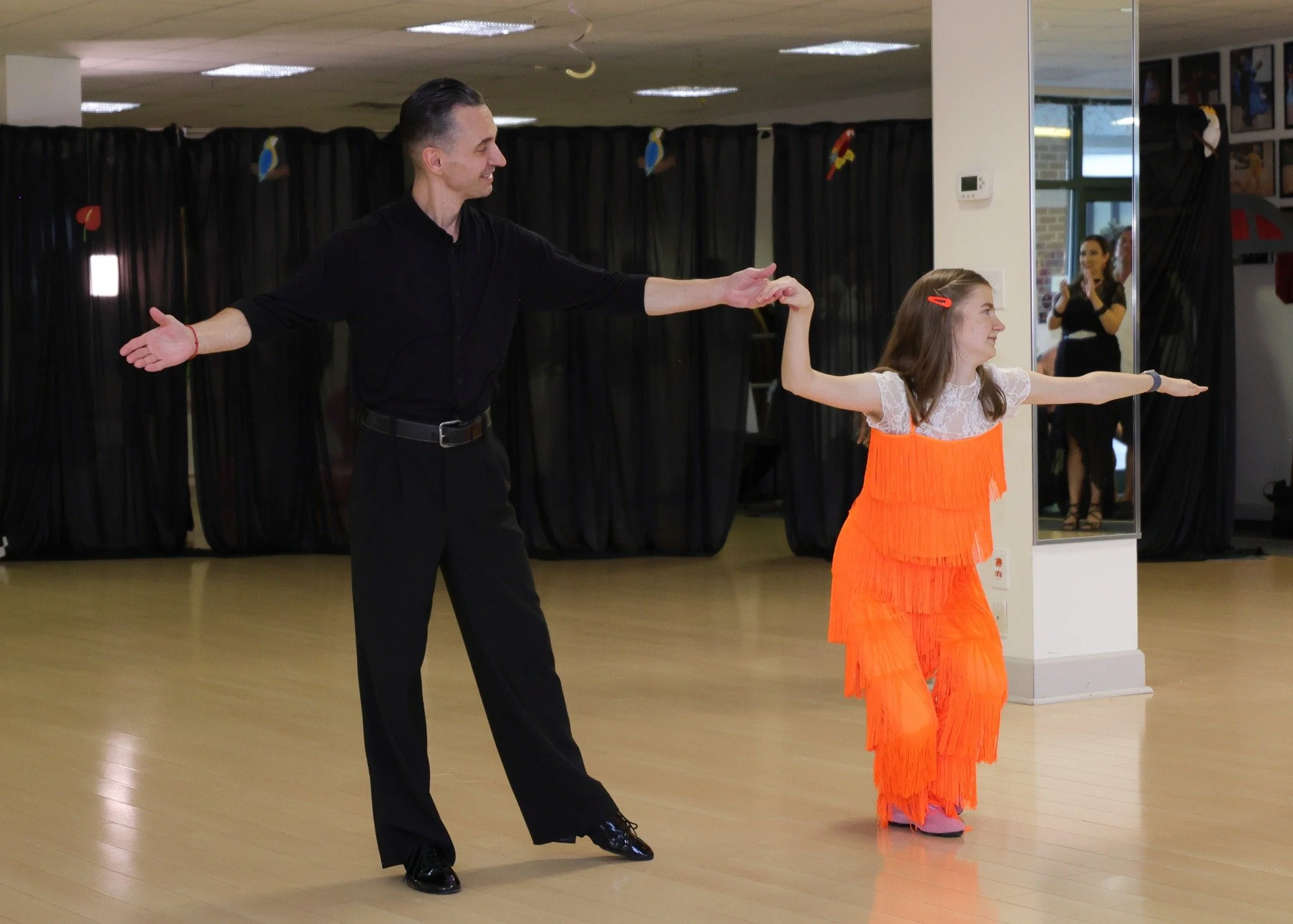 A dancer in orange performs beside her partner at the Summer Showcase