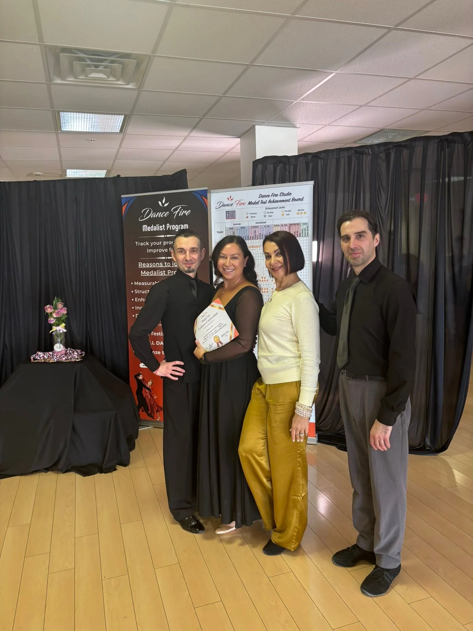 A spring Medal Achievement participant poses with instructors beside the studio backdrop
