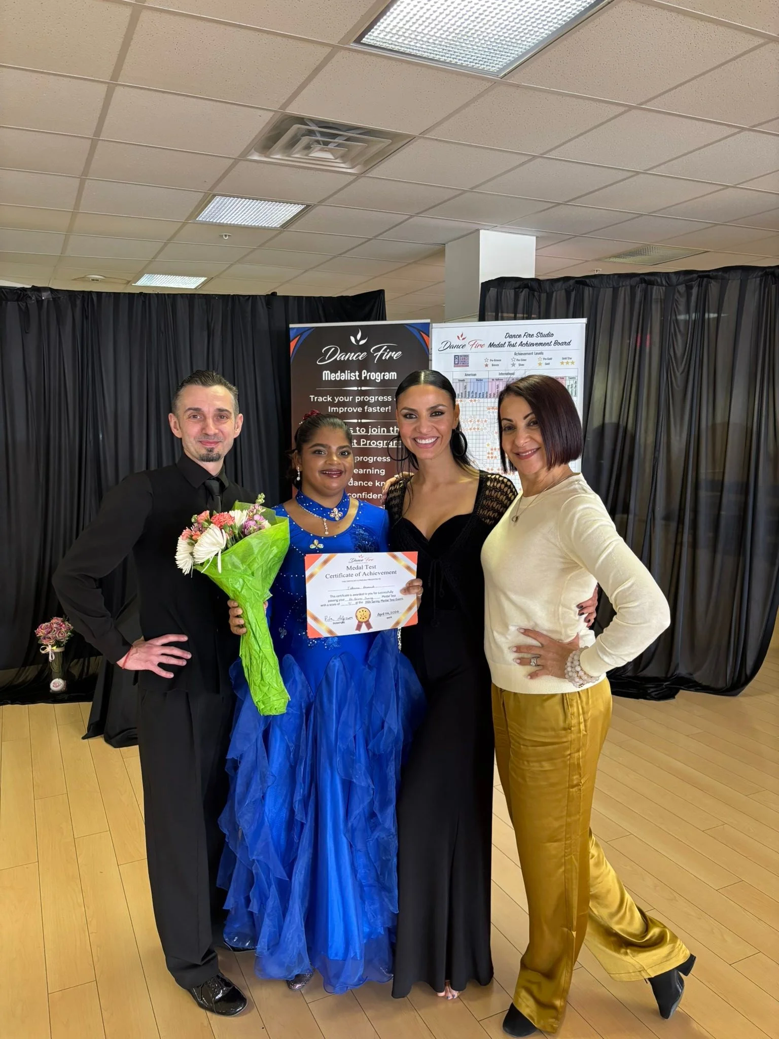 A student in a blue ballroom dress displays her Medal Achievement certificate