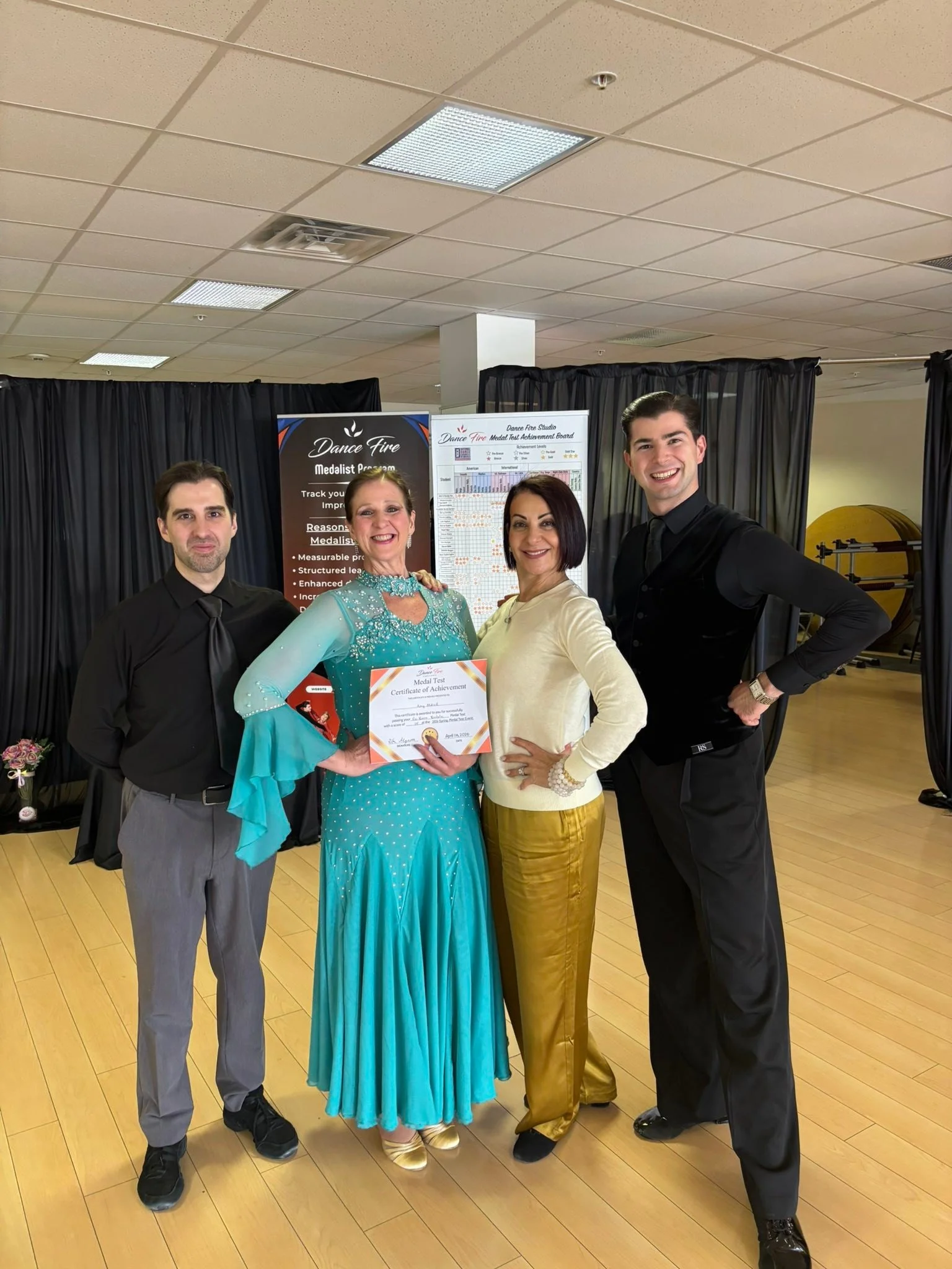 A student in a turquoise dress holds her certificate with the assessment team