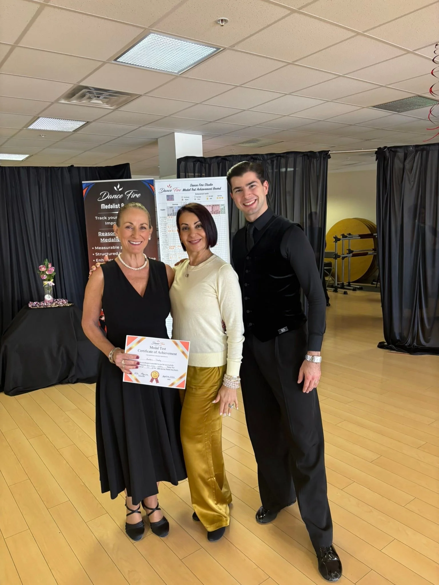 A Medal Achievement participant in black holds her certificate beside the studio team