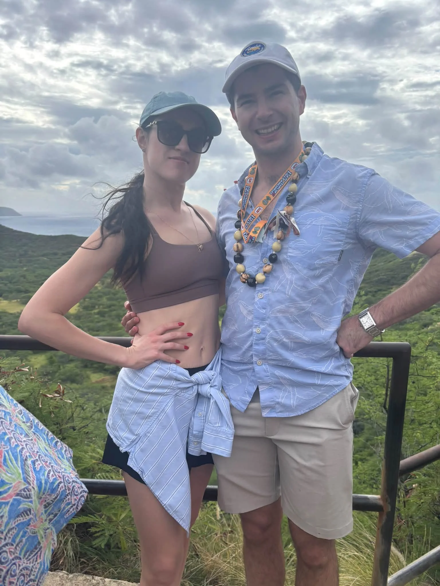 A pair of travelers poses above the Hawaii coastline