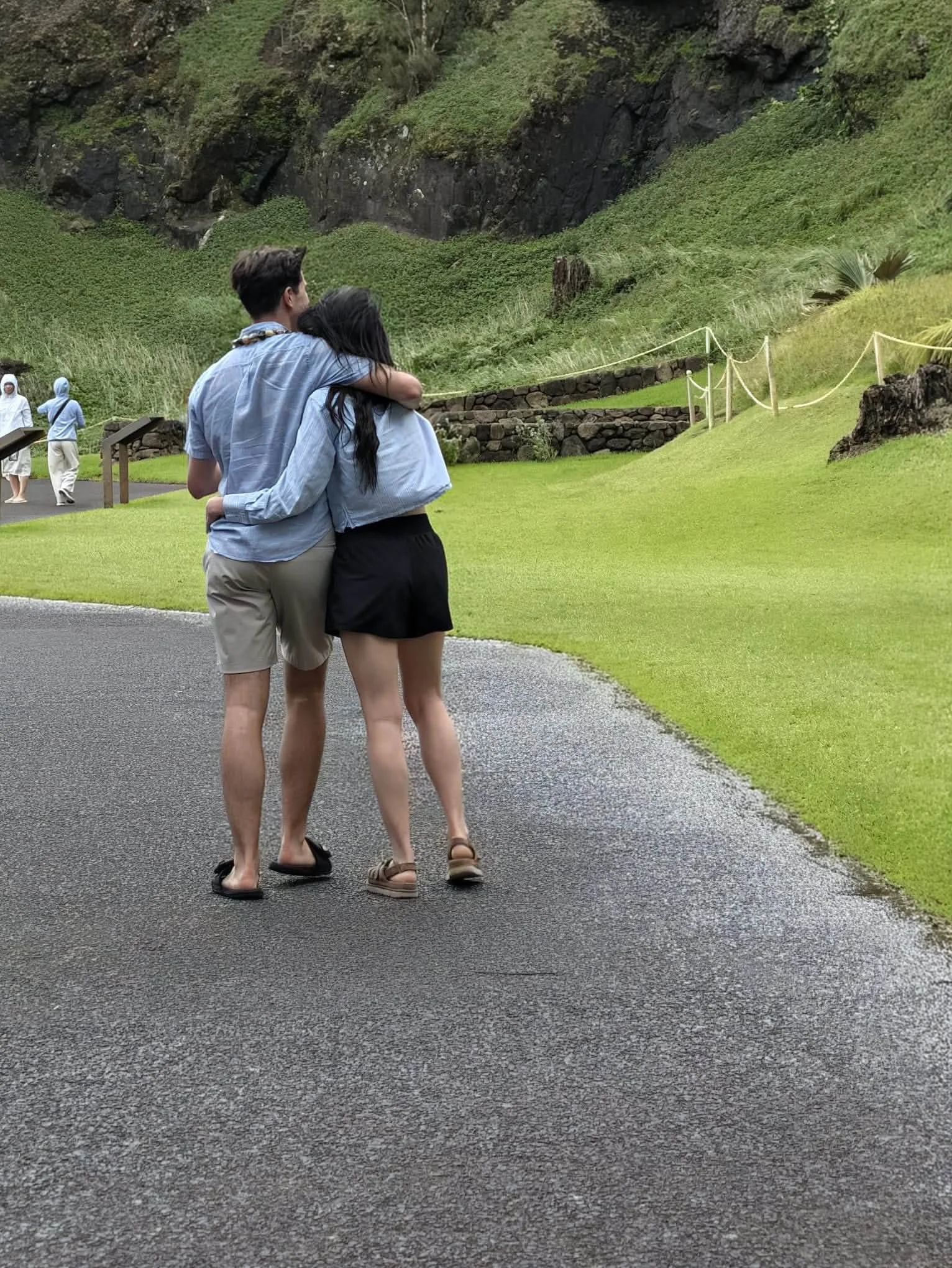 Two travelers walk along a landscaped path in Hawaii