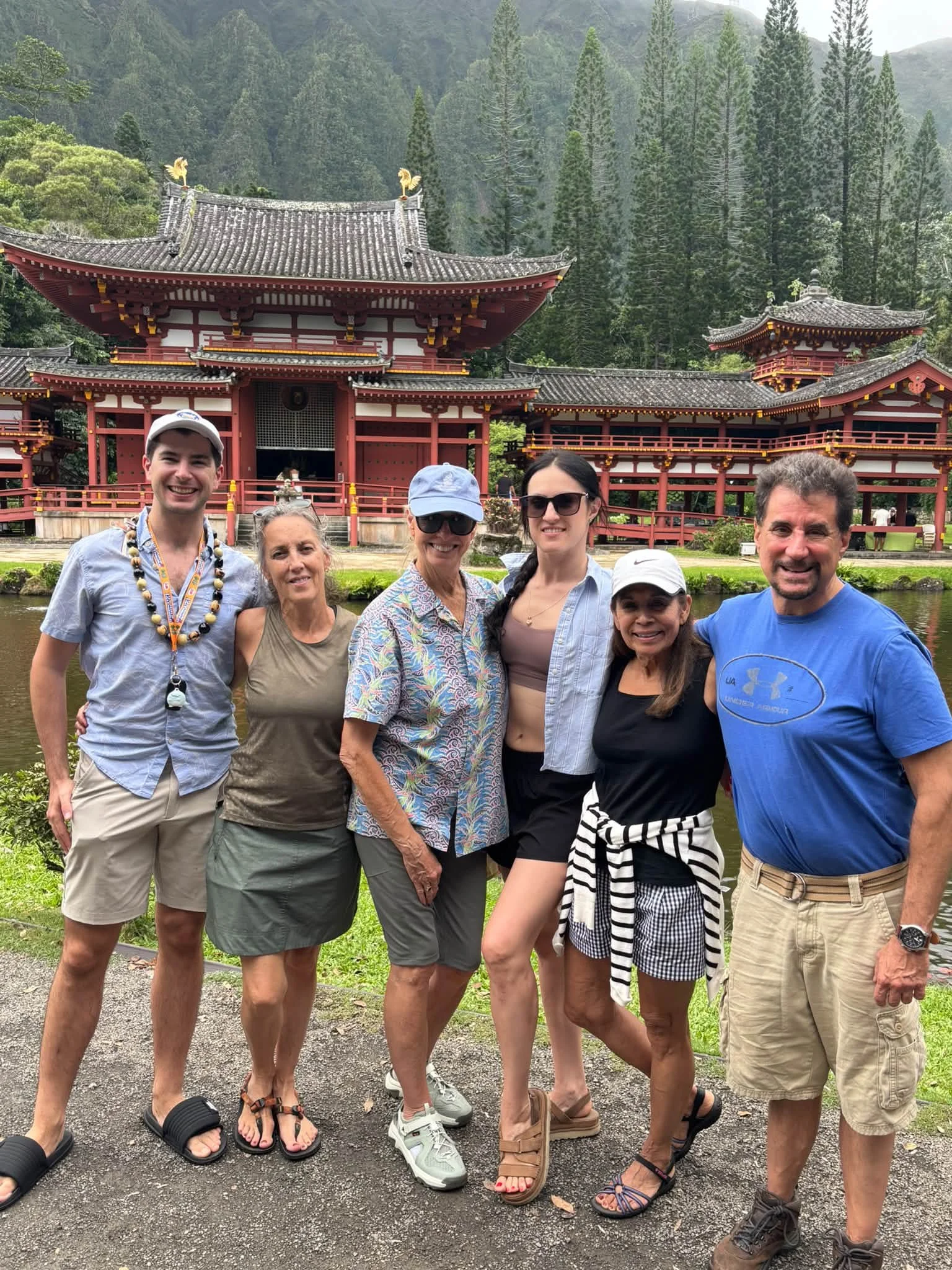 The travel group poses before a red temple-style building in Hawaii