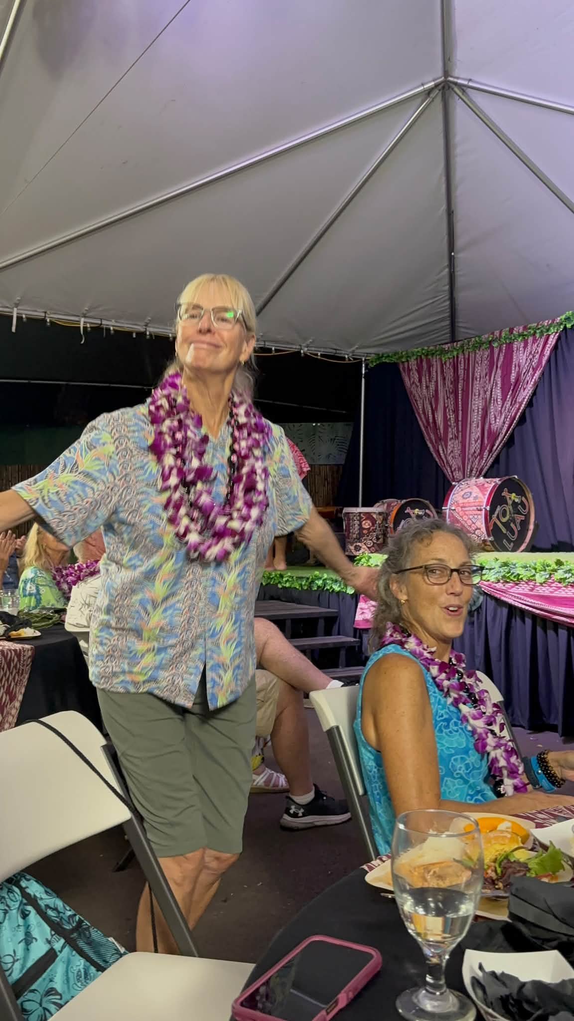 A Dance Fire traveler wearing leis stands beside the group’s outdoor table