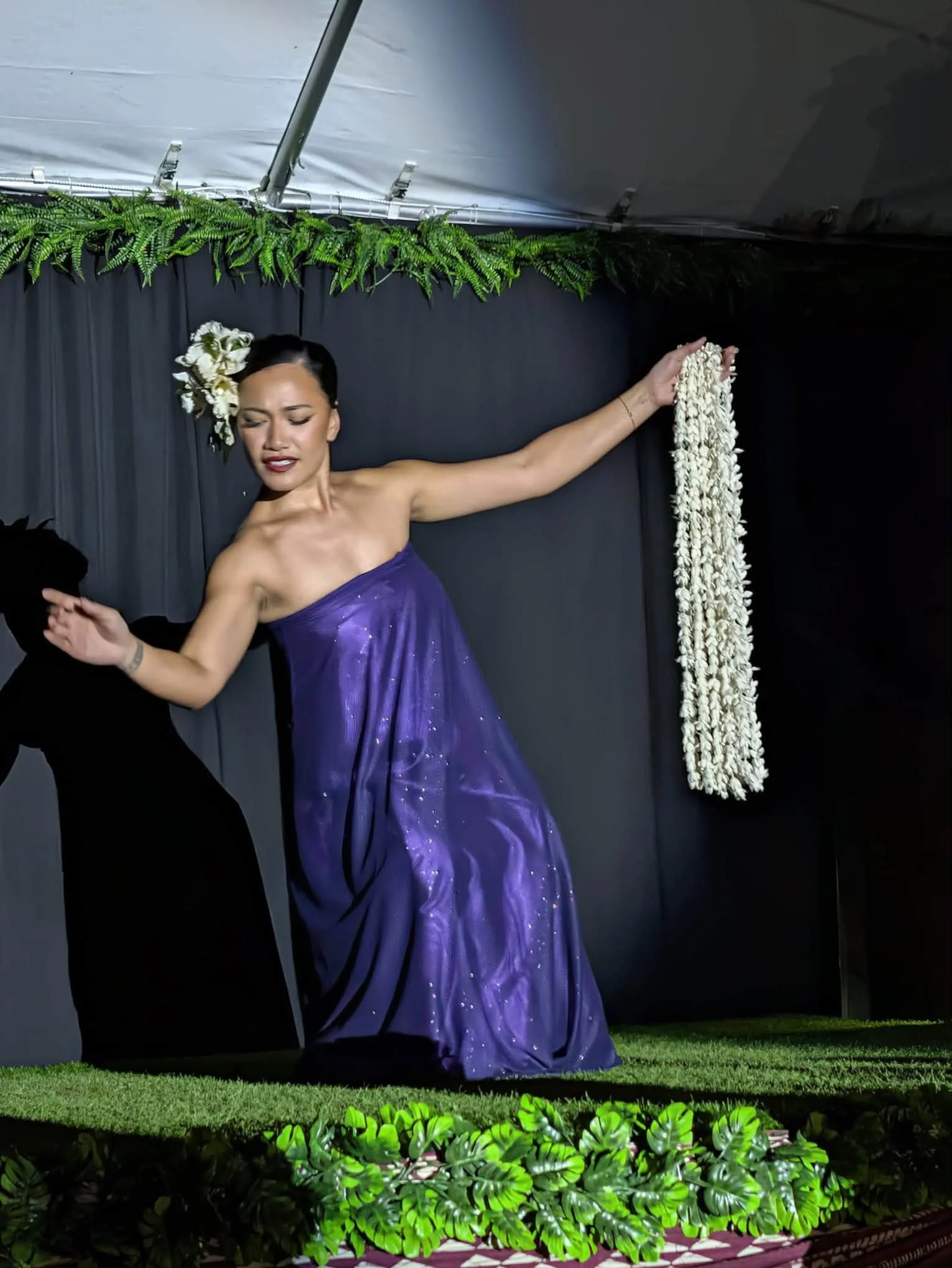 A performer in purple dances on a decorated stage in Hawaii