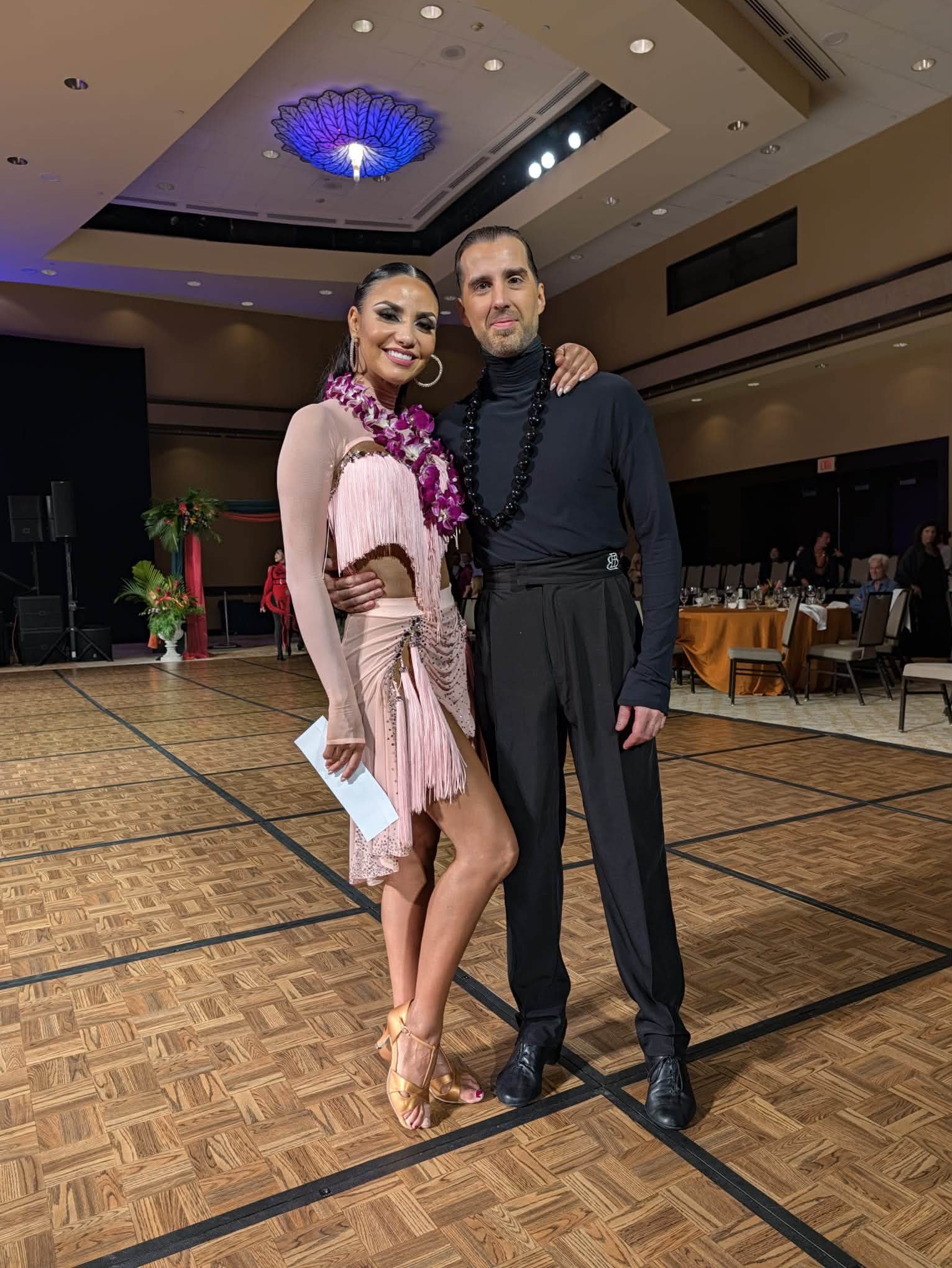 A Dance Fire competition pair poses in pink and black dance attire