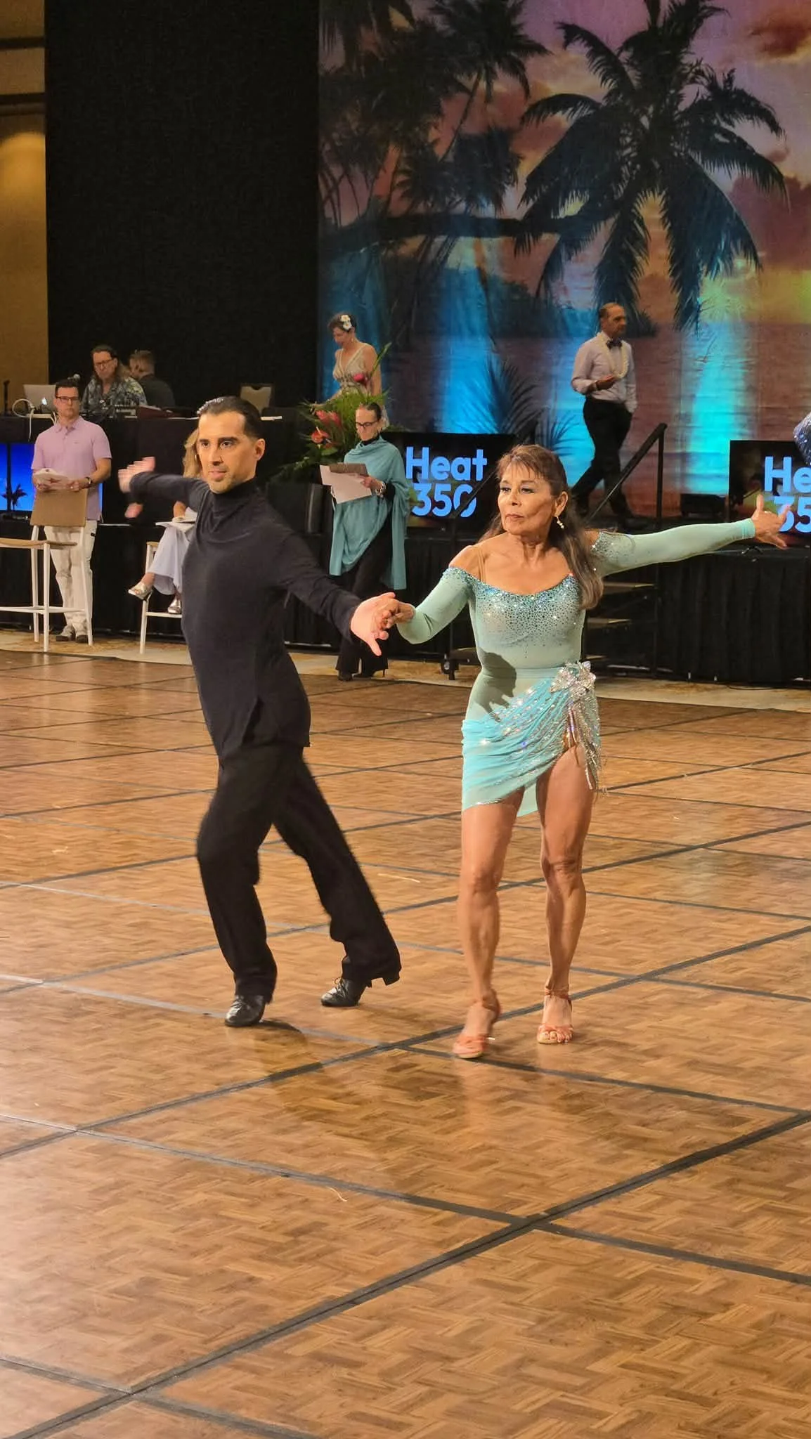 A couple in turquoise and black performs on the Hawaii competition floor