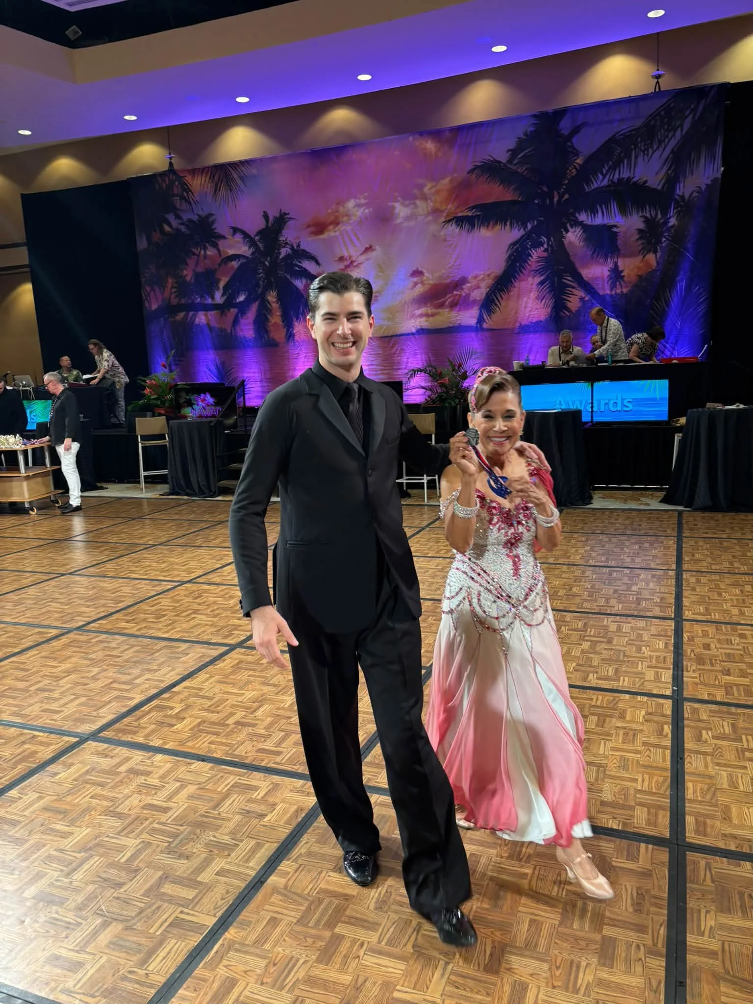 A competition pair walks together across the Hawaii ballroom floor