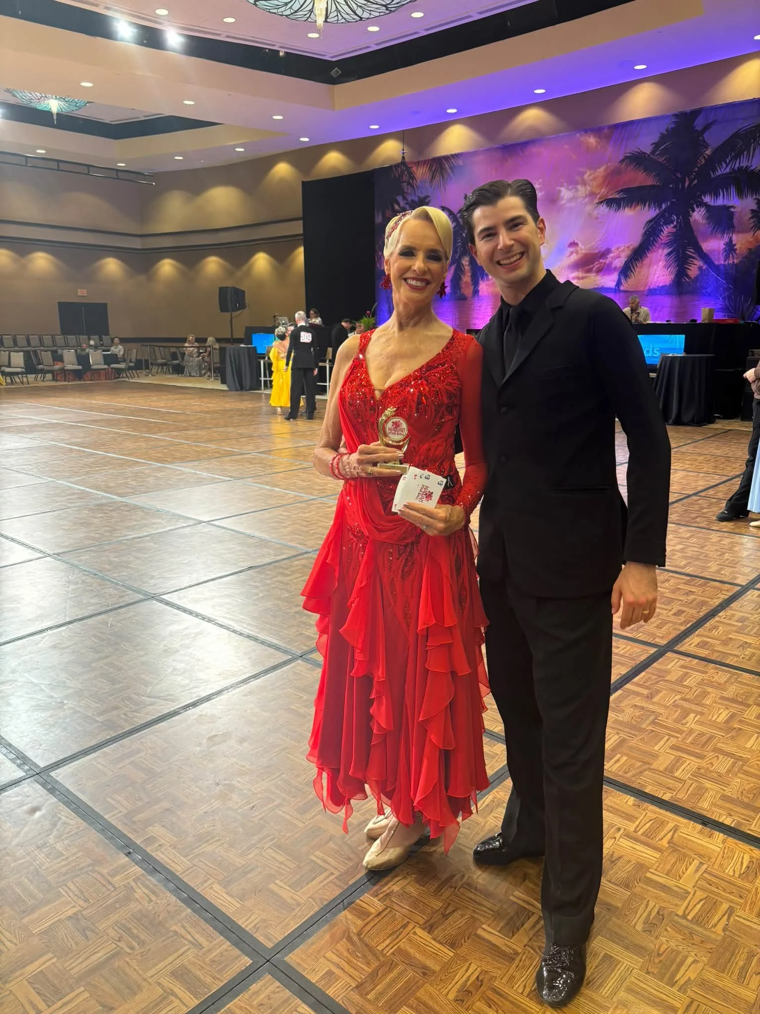 A Dance Fire ballroom pair poses in red and black competition attire