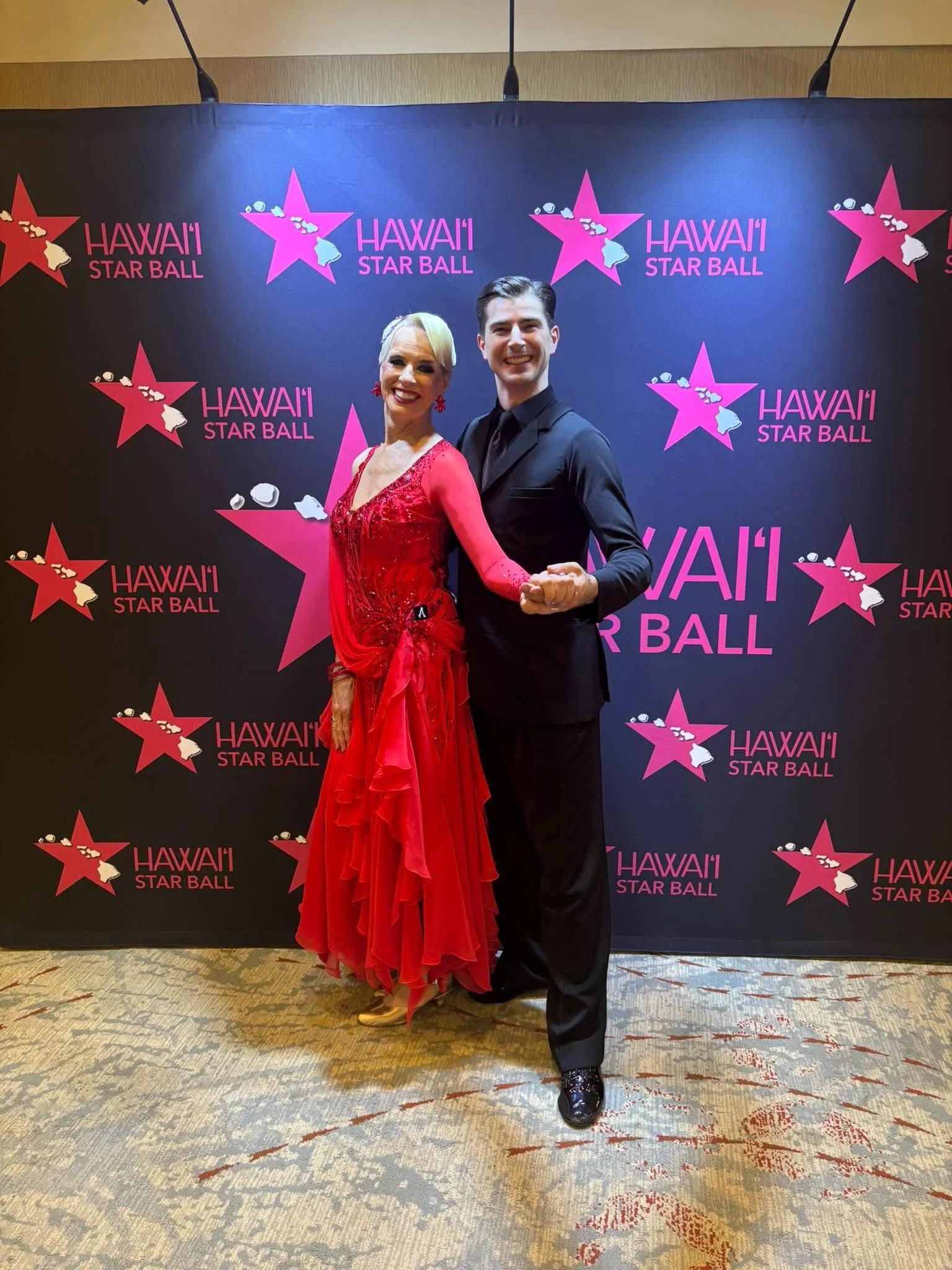 A Dance Fire ballroom pair poses at the Hawaii Star Ball backdrop