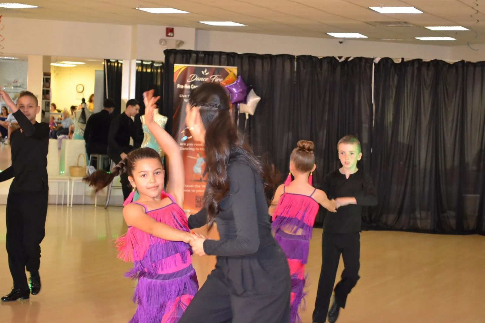 Young dancers in purple costumes perform together at the recital