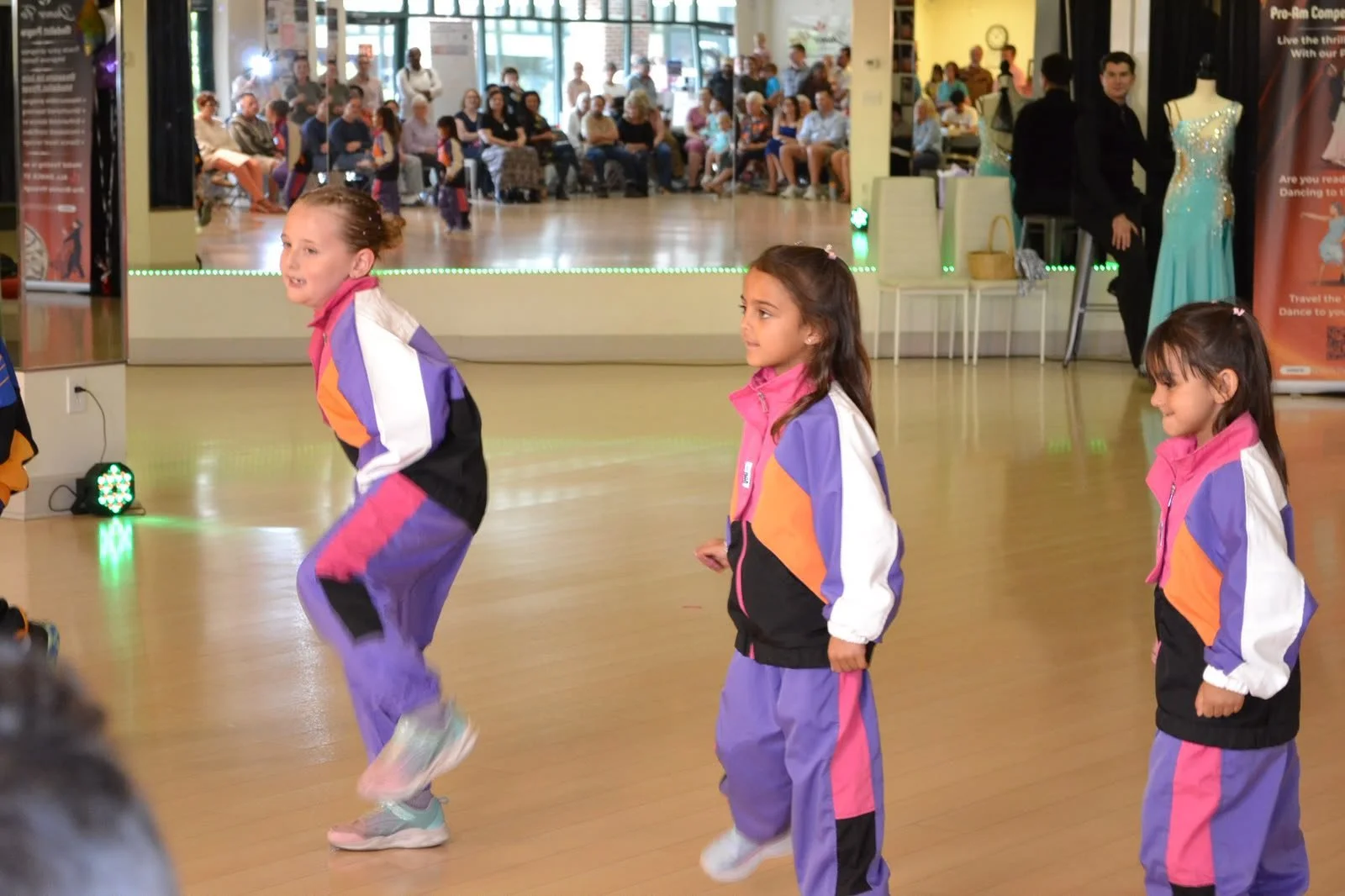 Children in purple costumes dance together in a recital formation