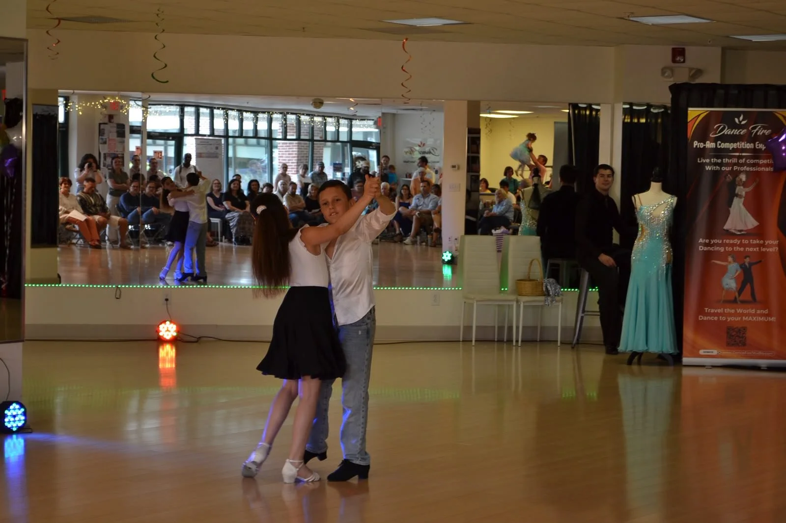 A youth dance couple performs on the mirrored Dance Fire studio floor