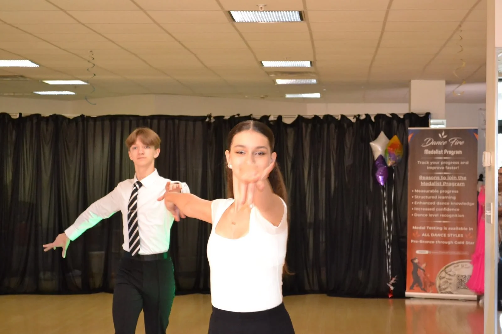 Young ballroom partners dance toward the recital audience