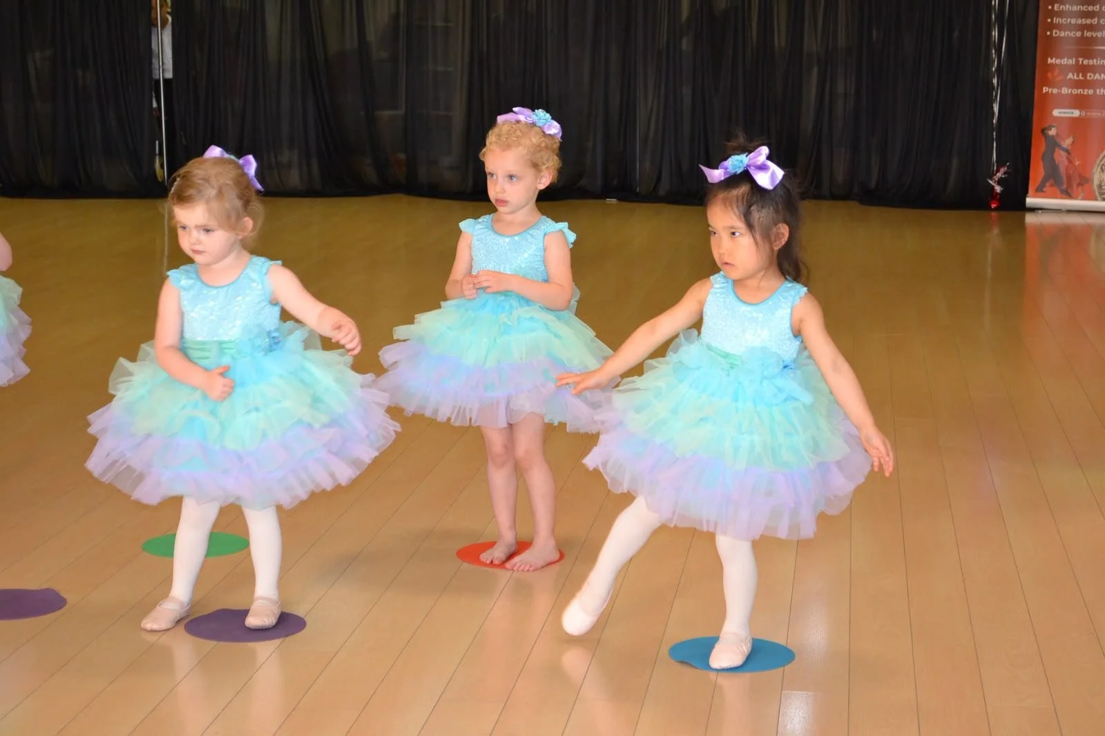 Young ballet performers dance together in pastel tutus
