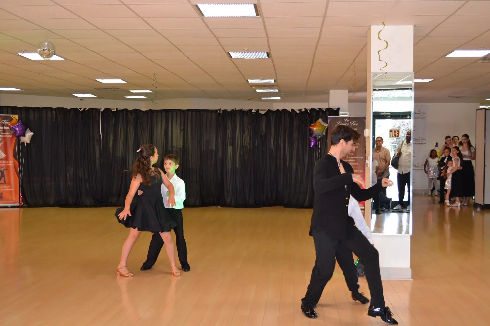 Young dance partners perform across the studio floor before the recital audience