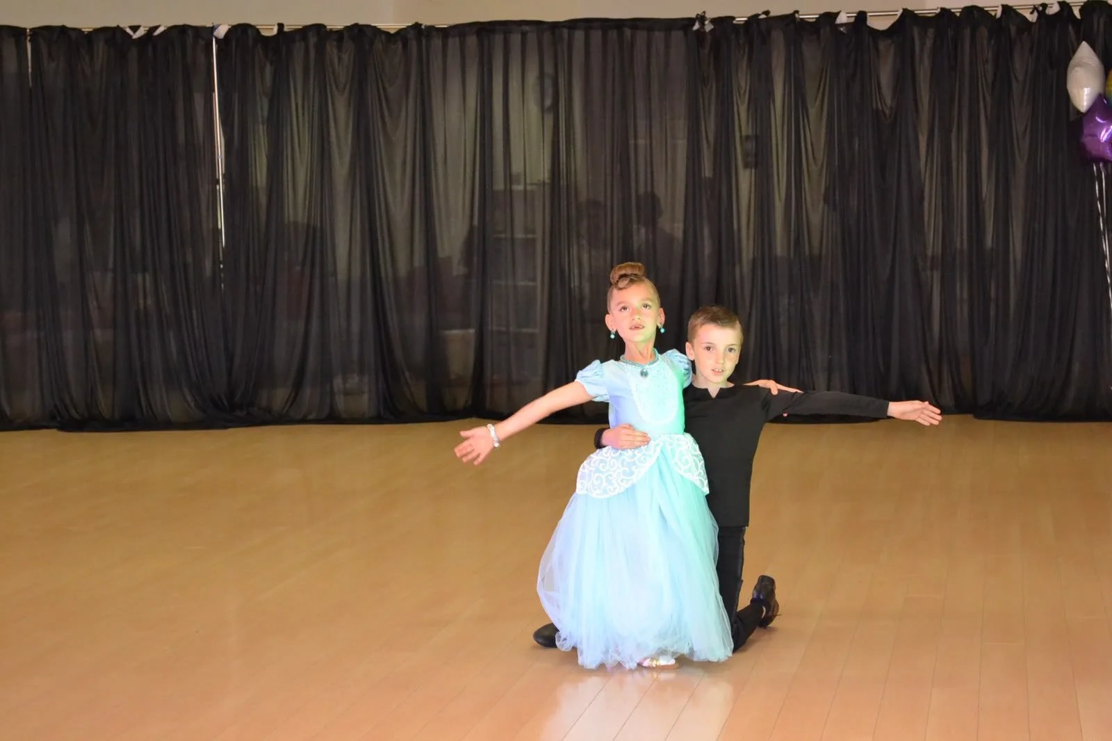 A young ballroom couple dances with a flowing pale blue dress